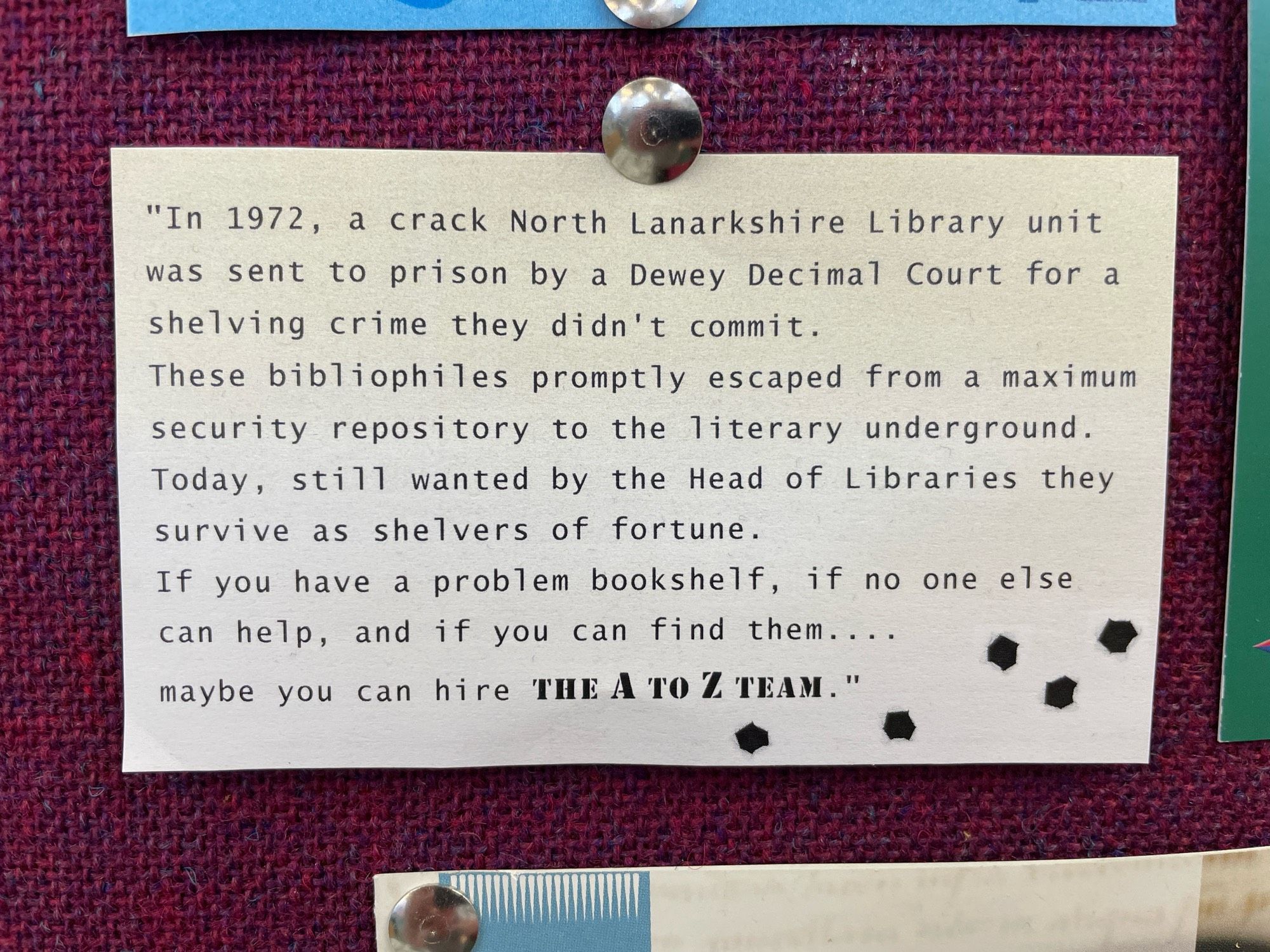 A teeny tiny bit of paper doodled up to look old and featuring a few fake bullet holes at the bottom right. 
(Read in the style of The A Team into)

"In 1972, a crack North Lanarkshire Library unit was sent to prison by a Dewey Decimal Court for a shelving crime they didn't commit.
These bibliophiles promptly escaped from a maximum security repository to the literary underground.
Today, still wanted by the Head of Libraries they survive as shelvers of fortune.
If you have a problem bookshelf, if no one else can help, and if you can find them.... maybe you can hire THE A TO Z TEAM."

🎶 Nah na nah. Duh duh duuh. Da dada da d’ daa. Nah nanana nah! 🎶