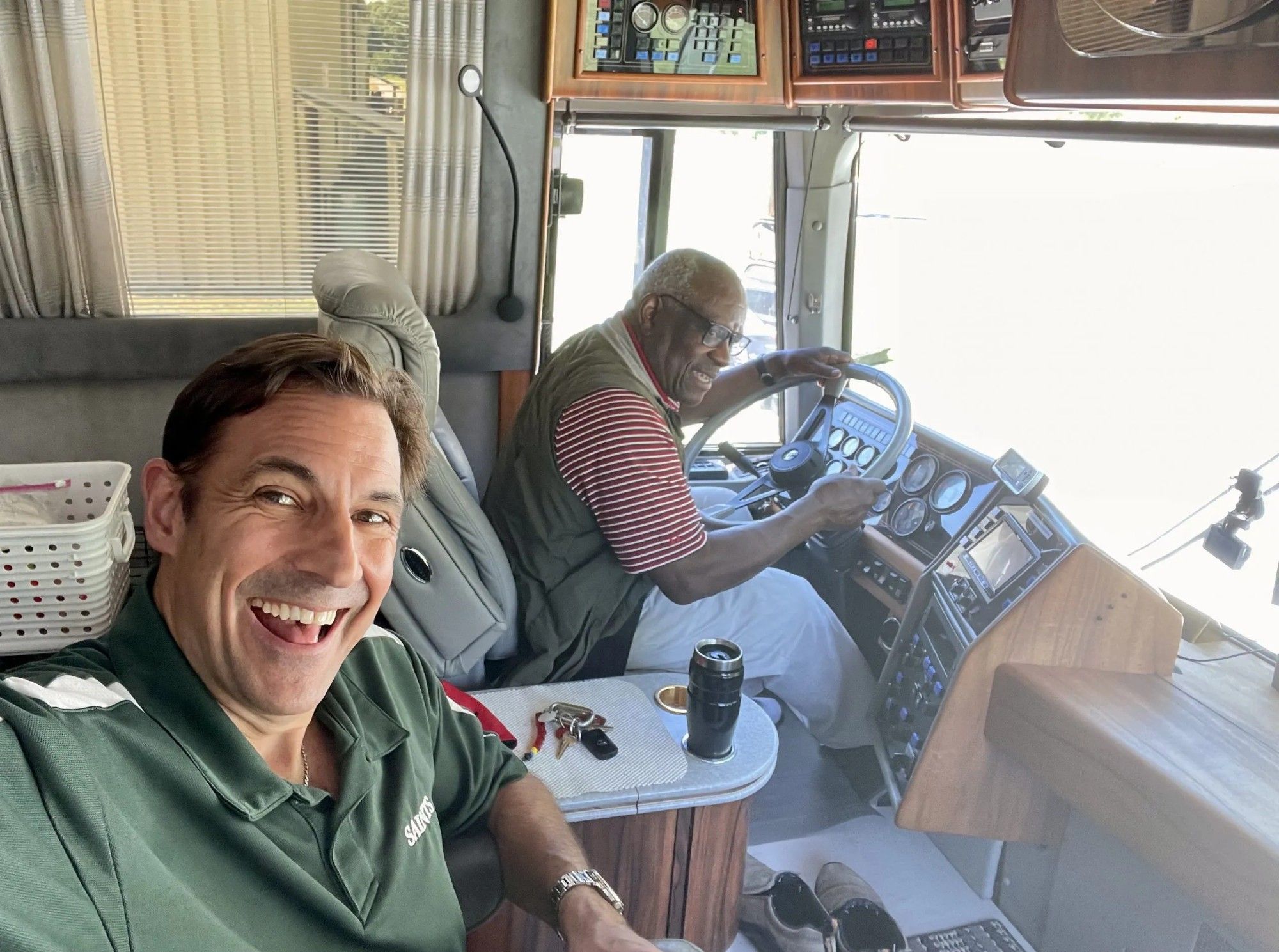 Justice Clarence Thomas behind the wheel of his Prevost motorhome with a Washington Examiner feature reporter laughing in the foreground