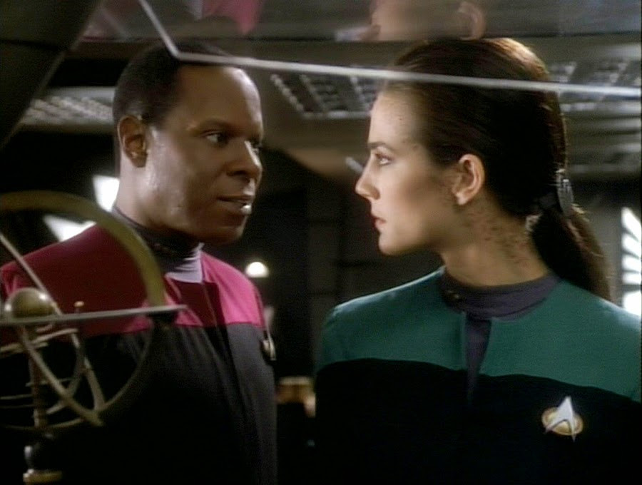 Sisko and Dax in Star Trek: Deep Space Nine. Their uniforms are black with red and blue shoulders, respectively. 