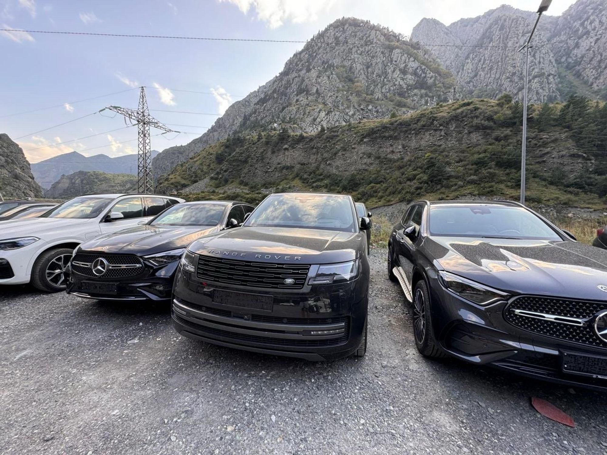 A picture of new Range Rovers and Mercedes on the Georgia/Russia border. The Georgian mountains are in the background.