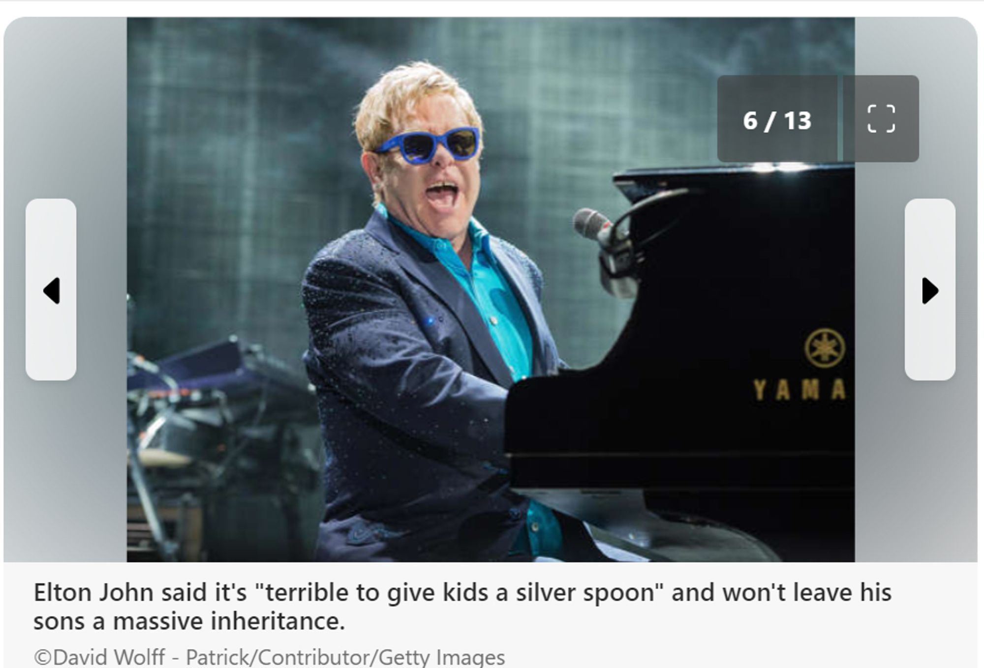 Picture of Elton John, at a black yamaha grand piano.
He is wearing a blue suit, no tie, turquoise shirt and blue sun glasses (his hair is blond)
Elton John said it's "terrible to give kids a silver spoon" and won't leave his sons a massive inheritance.
©David Wolff - Patrick/Contributor/Getty Images