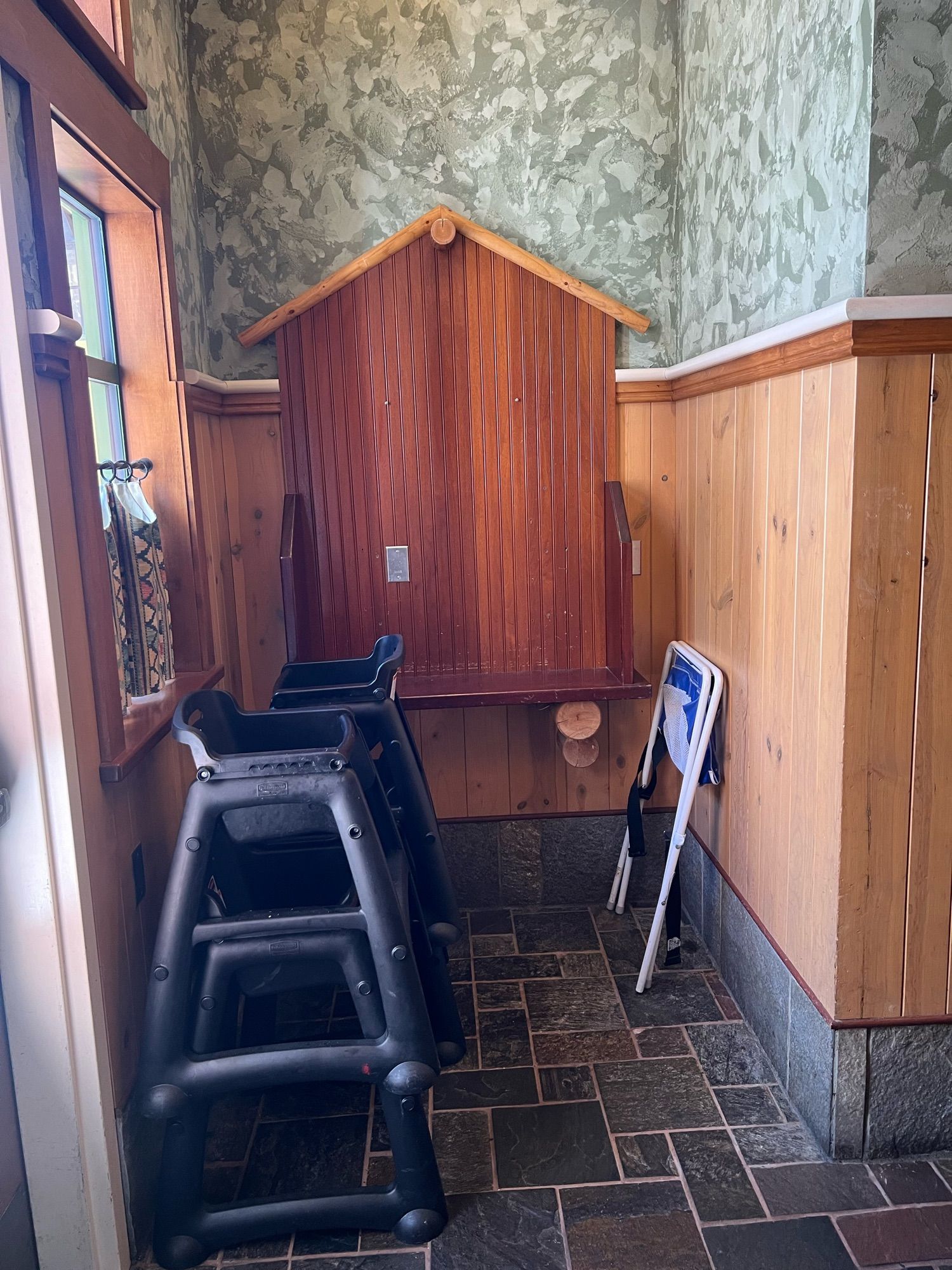 A table which used to be used for a telephone, now missing a telephone and with chairs stacked in front of it.