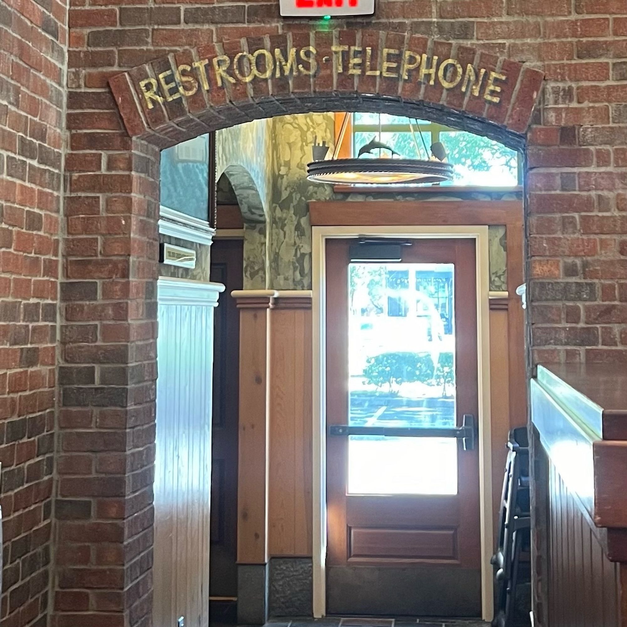 A photo of an archway inside a restaurant with a sign above it saying “Restrooms - Telephone”