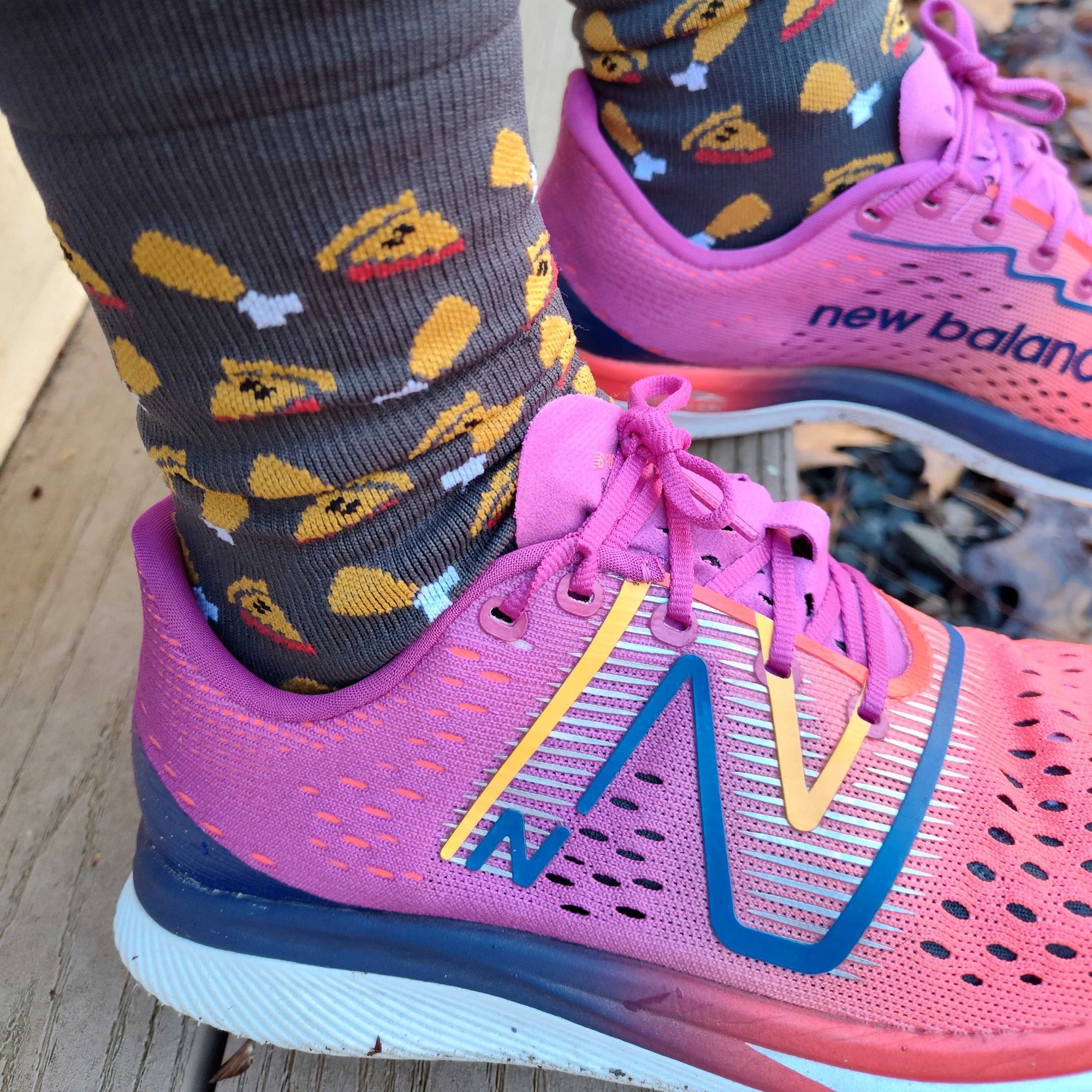 Ankles in pink and blue running shoes and socks printed with turkey legs and slices of pie.