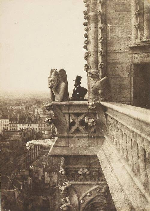 Man stands behind sad looking gargoyle 