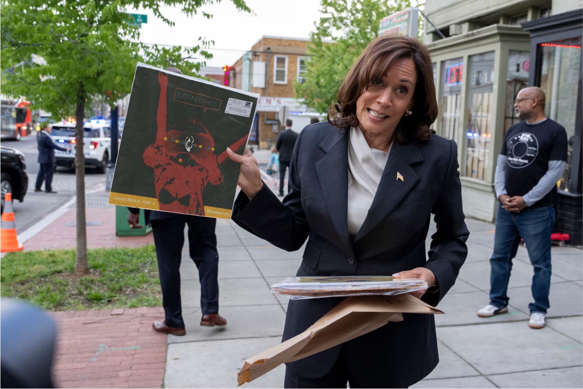 An edited image of Vice President Kamala Harris on a sidewalk in Washington, D.C., appearing to hold (but not in real life holding) the record 'Handcream for a Generation' by Cornershop.