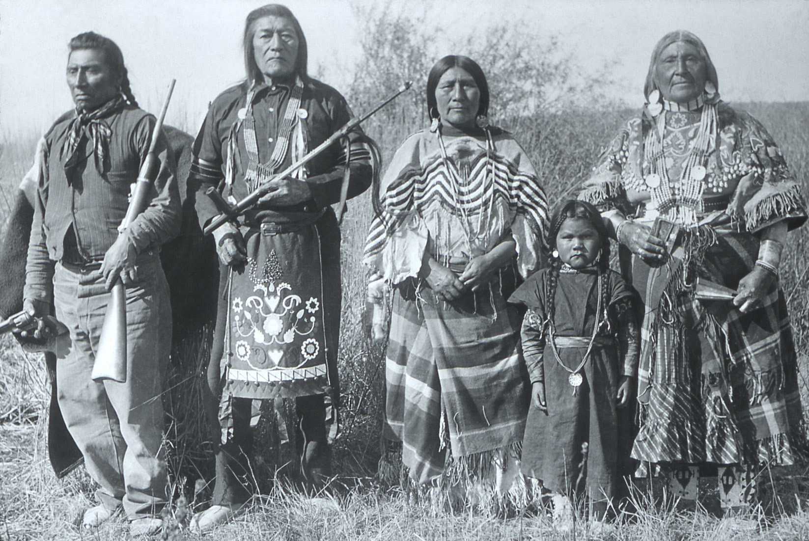 Bannock Indians in Idaho, not sure of the date but it looks late 19th century. Men, women and a small girl wear a beautiful assortment of beaded, embroidered and fringed dress and jewelry.