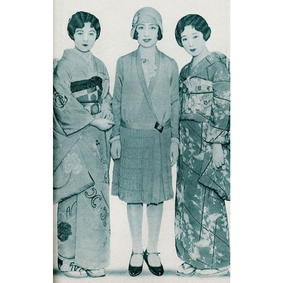 An image of fashions from the May 1930 Shufu No Tomo ("Housewife's Friend") Magazine, Japan. A cyan-tinted black-and-white photo of three young Japanese women, all with marcel-waved bobbed hair and 1920s style makeup. Two women in traditional kimonos flank one in a cloche hat, short flapper style dress, and t-strap high-heeled shoes.