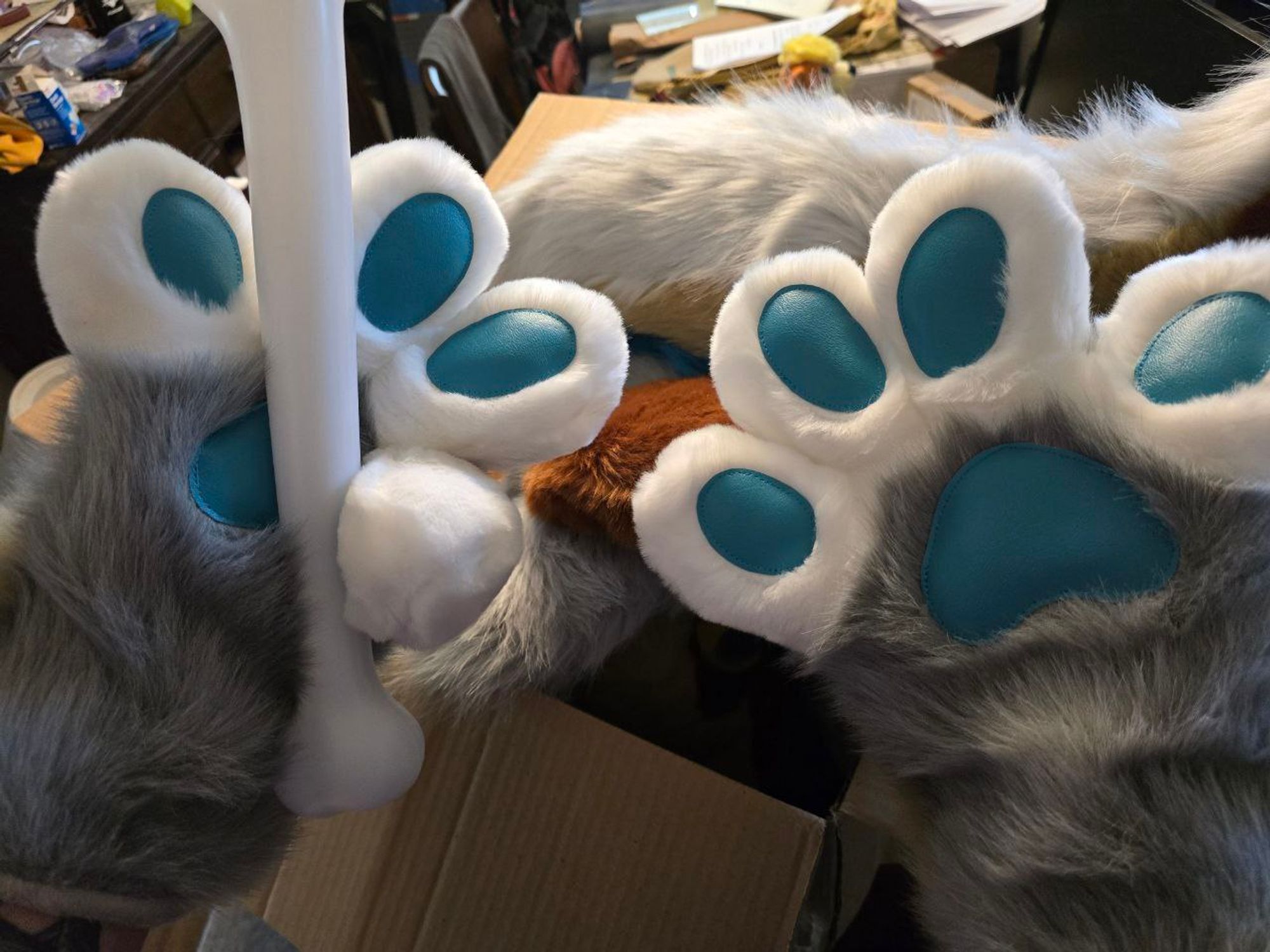 Someone wearing fursuit handpaws holding a plastic bone