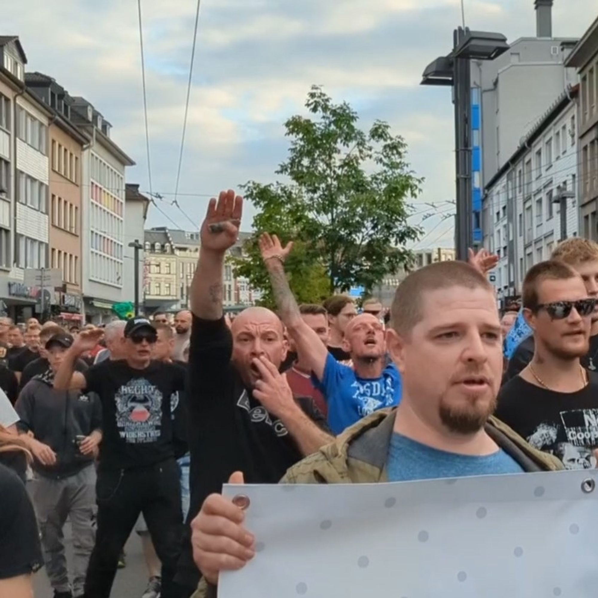 Eine Menschenmenge. (Der rechte Aufmarsch in Solingen gestern.) Mehrere Männer gestikulieren wild. Im Zentrum eine Person, die einen Hitlergruß zeigt und sich gleichzeitig zwei Finger unter die Nase hält.