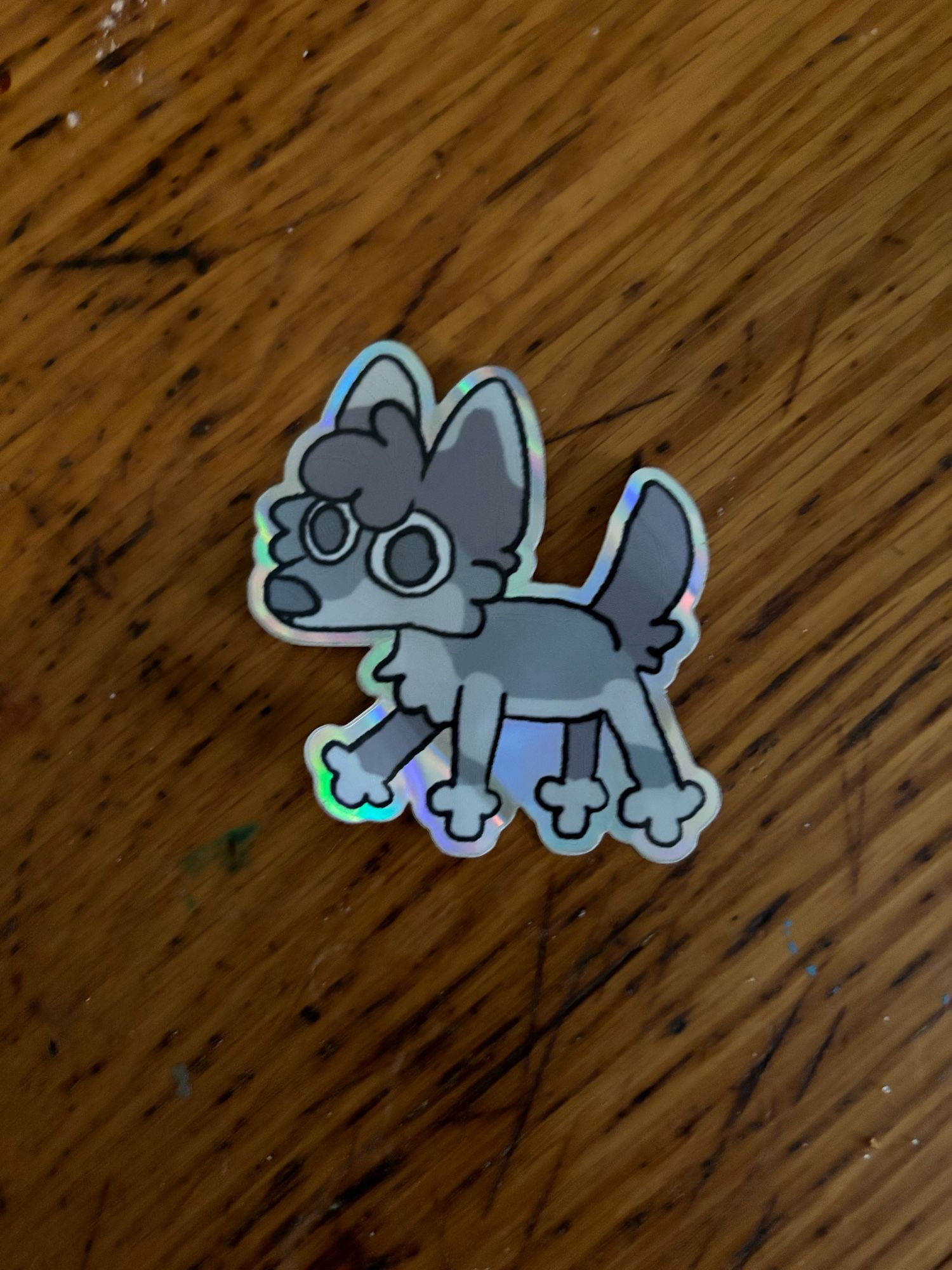 A sticker of someone’s cartoony wolf against a wood kitchen table surface.