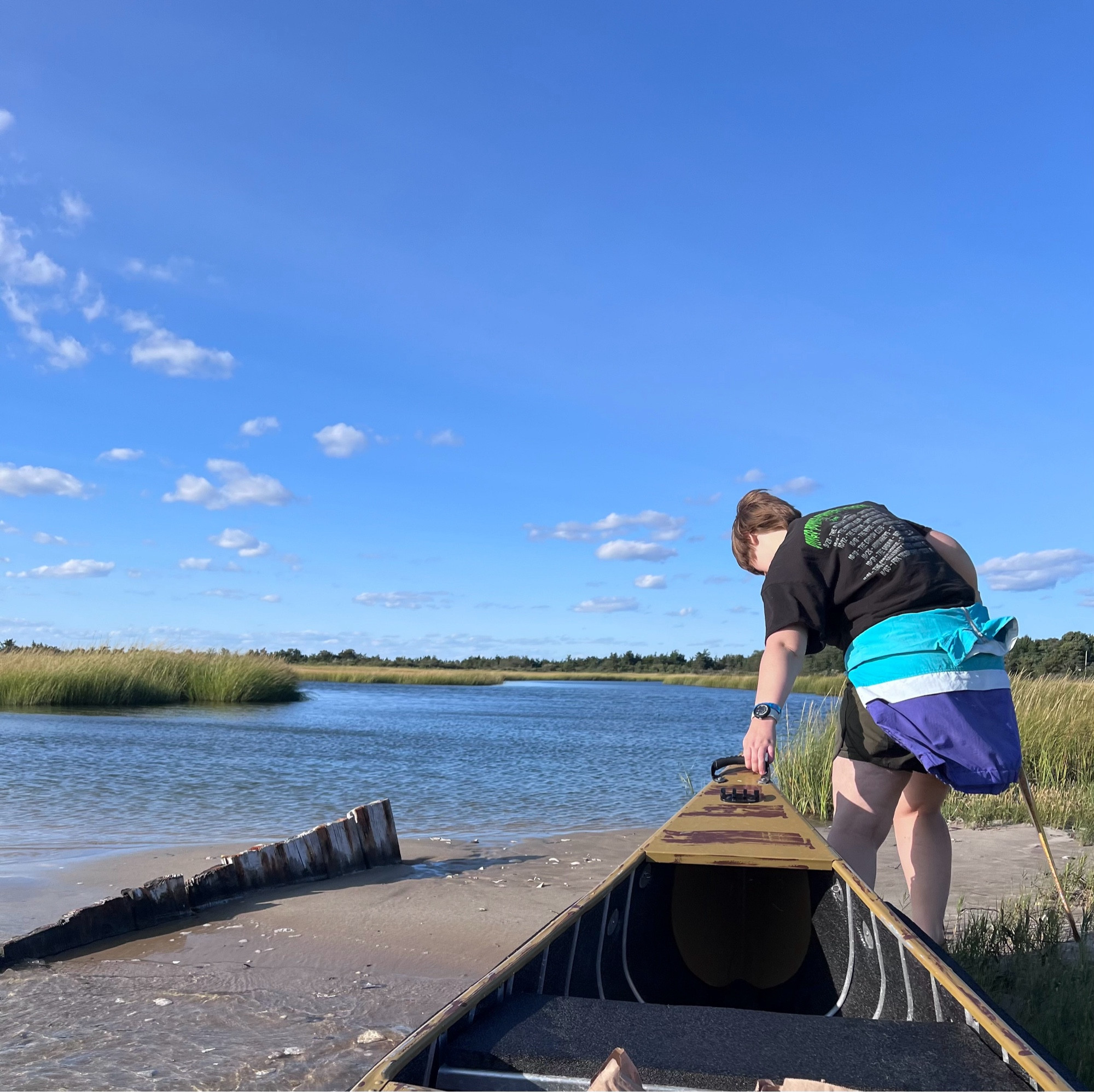 A woman pulls a canoe out of the water