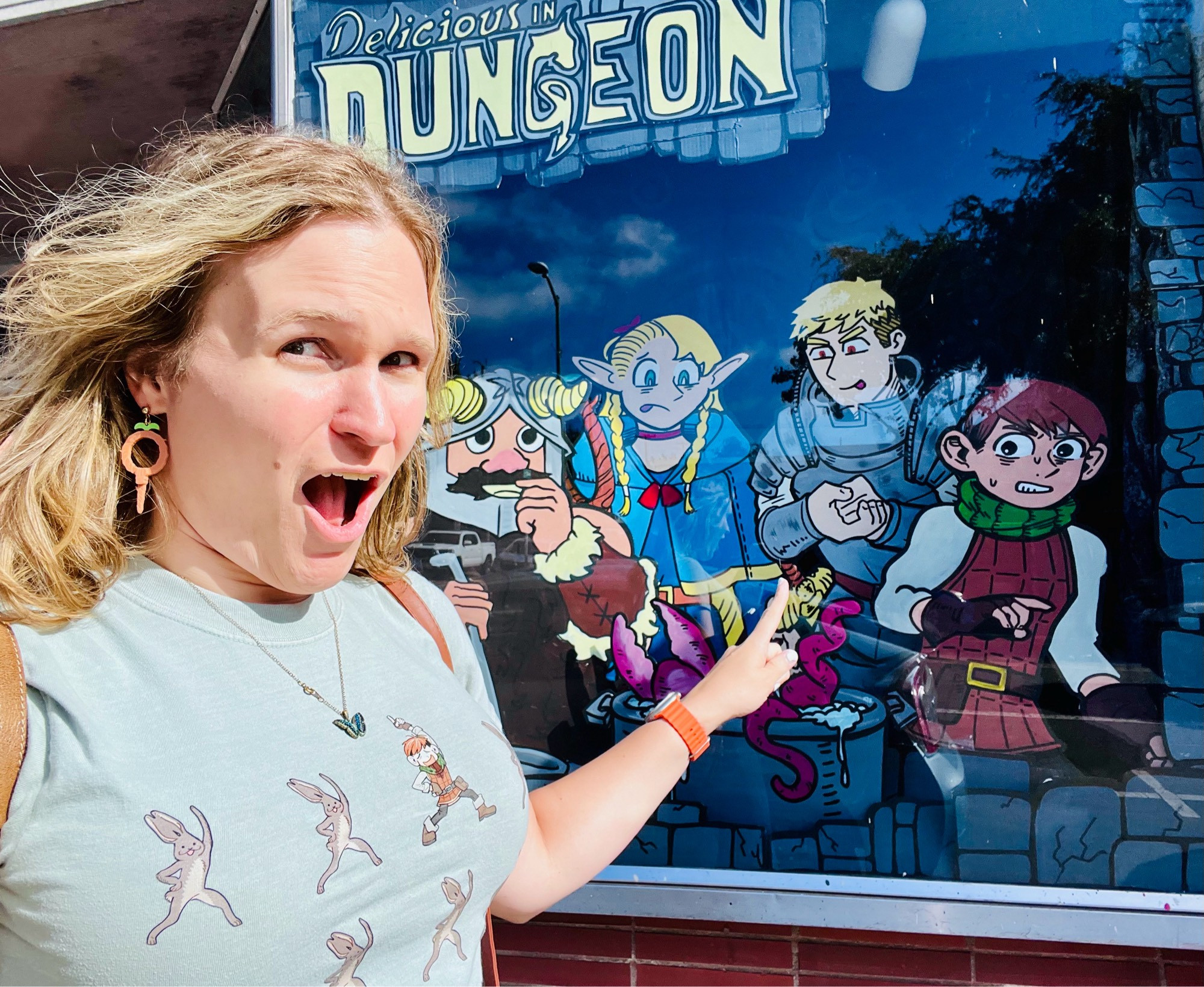 A middle aged woman points at an illustration of Laios from Dungeon Meshi