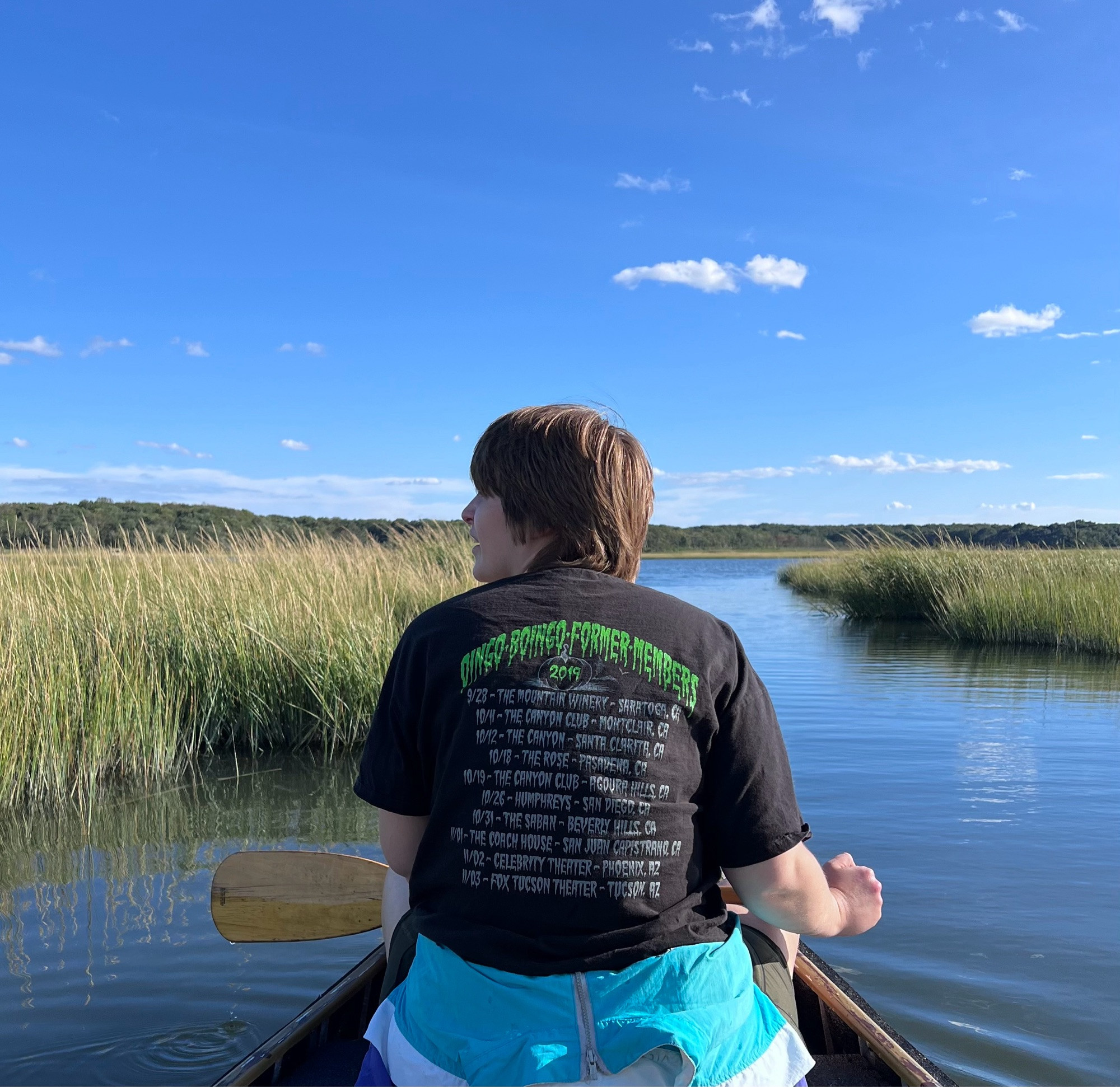 A woman sits in a canoe overlooking a sea of salt hay