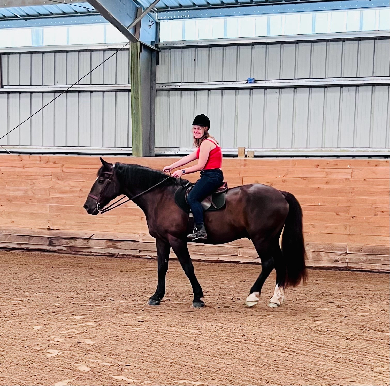 A middle aged woman riding a dark horse