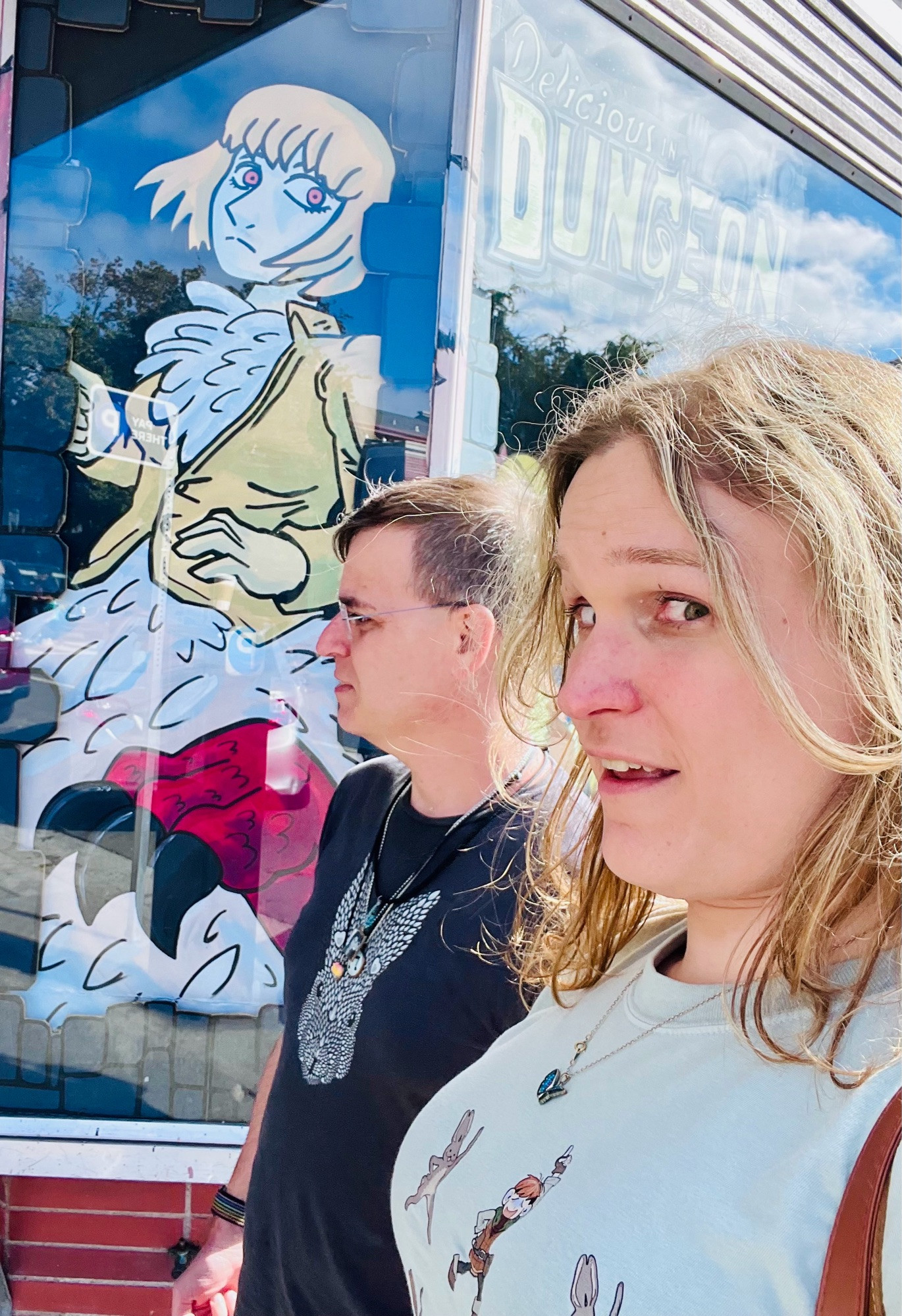 A window mural of Falin from Dungeon Meshi with a woman and a man in the foreground