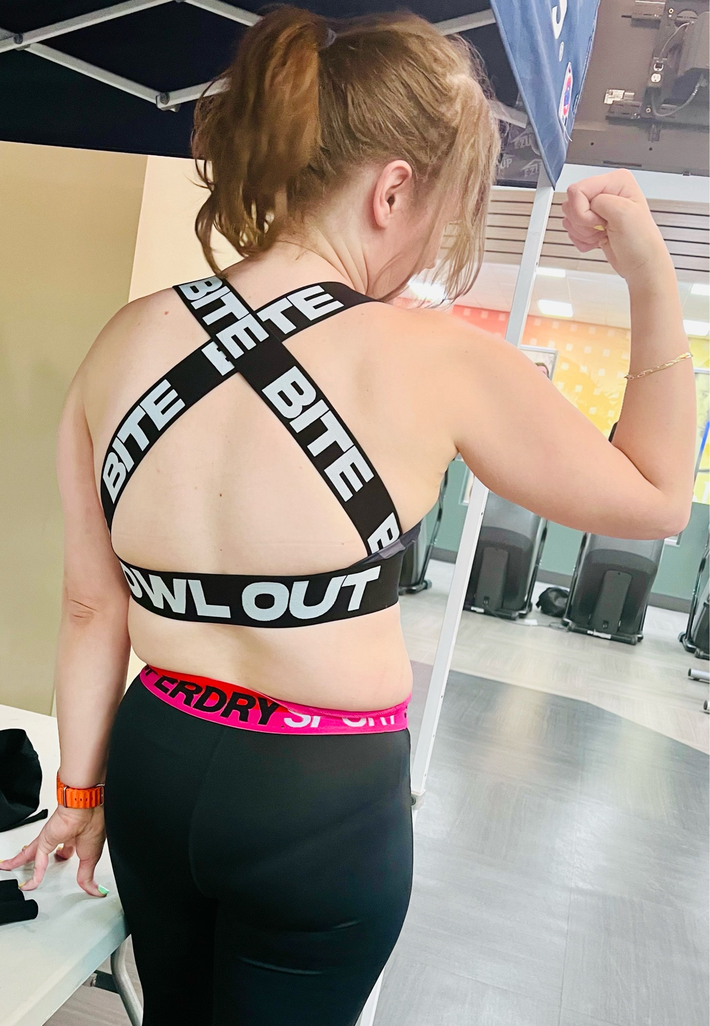 The back of a sports bra on a woman the text printed on the bands reads “BITE”