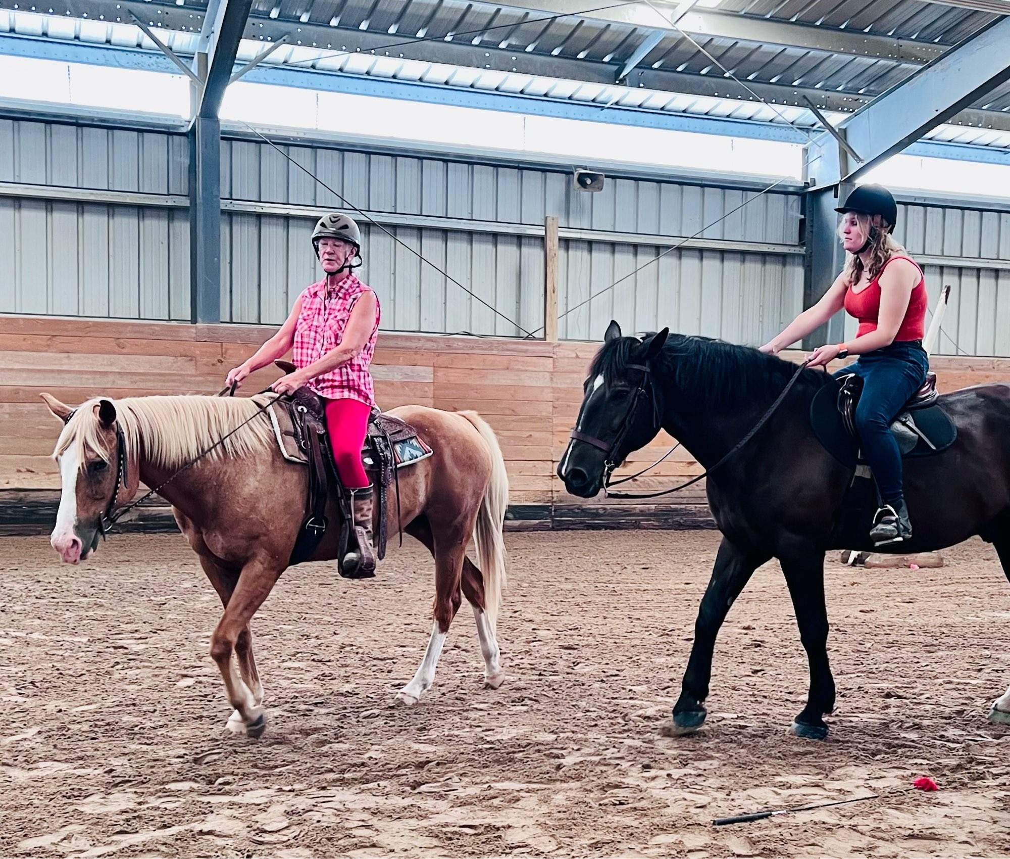 Two women riding horses indoors