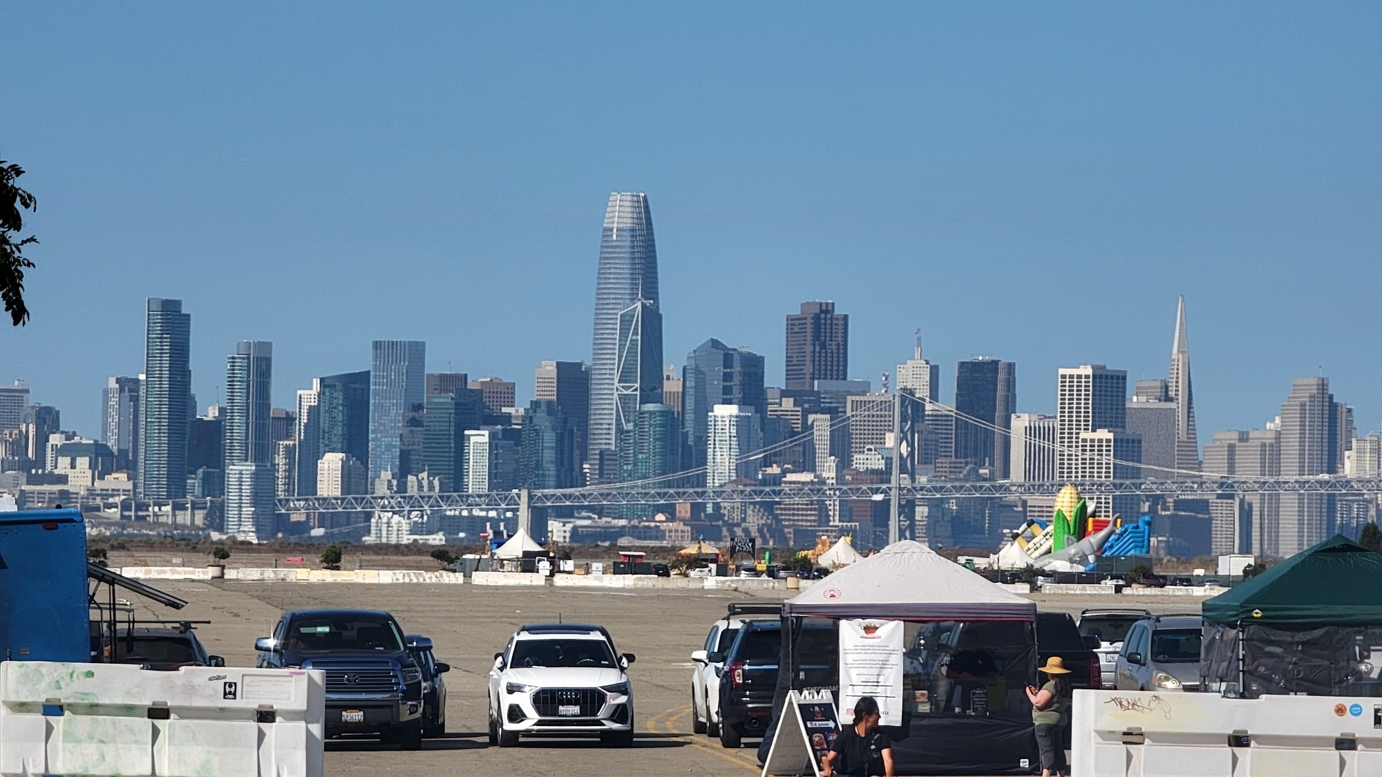 San Francisco skyline in the background, with cars on a large paved area in the foreground