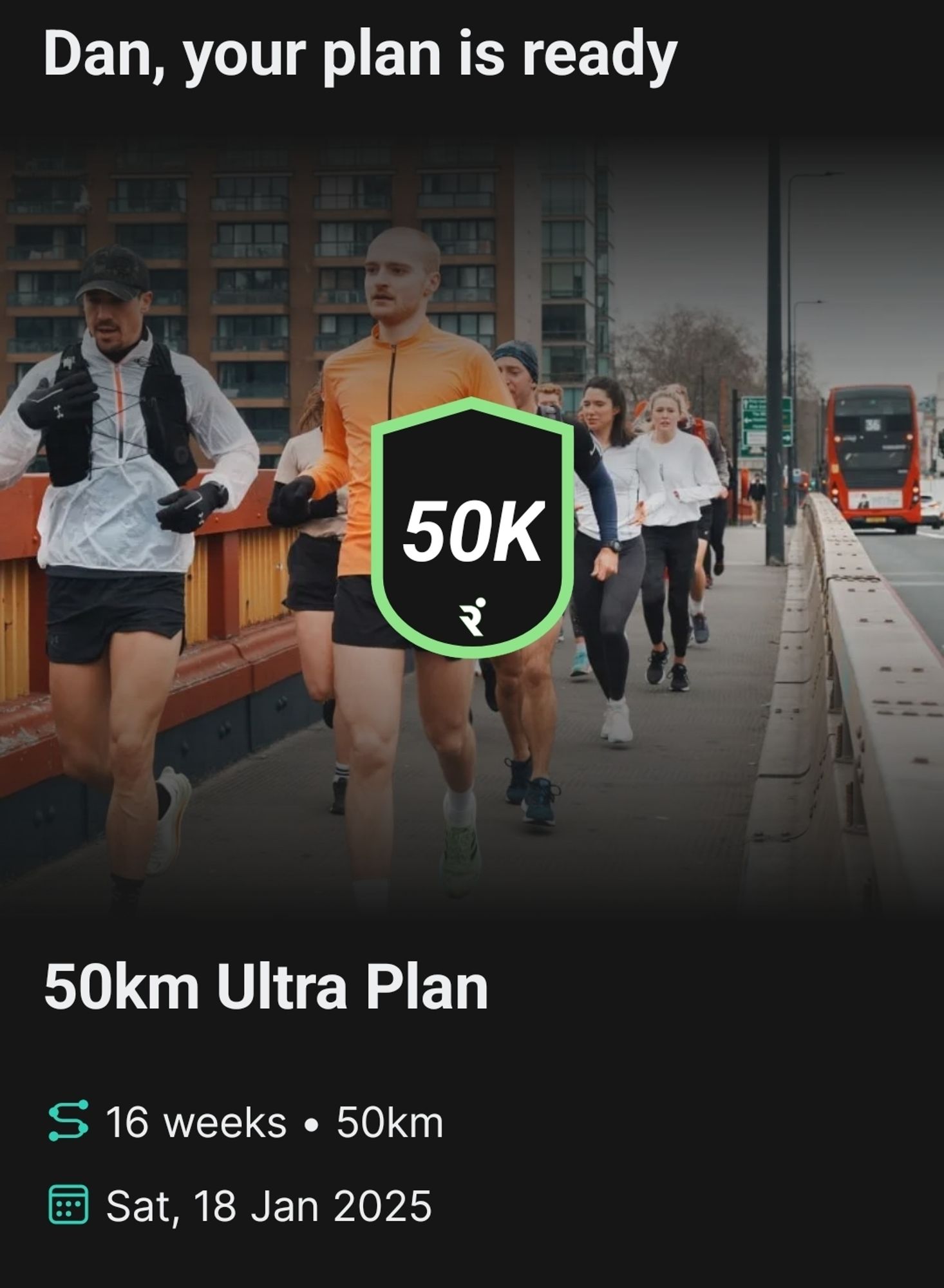 A screenshot from the Runna app. Ablack shield with green outline contains the white text, 50K. Behind the shield is a group of runners on a pavement. Below text states, "50km Ultra Plan. 16 weeks. 50km. Sat 18 Jan 2025".