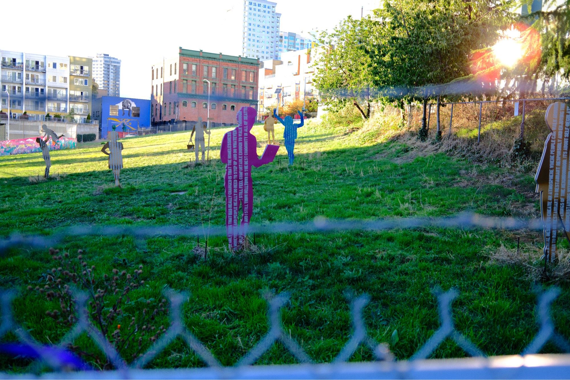 A field with cutouts seen through a fence topped with barded wire