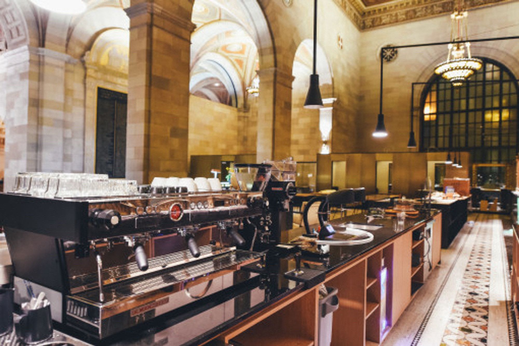 A spacious coffee shop, from the staff side of the counter. An espresso machine can be seen near the front (relative to camera).