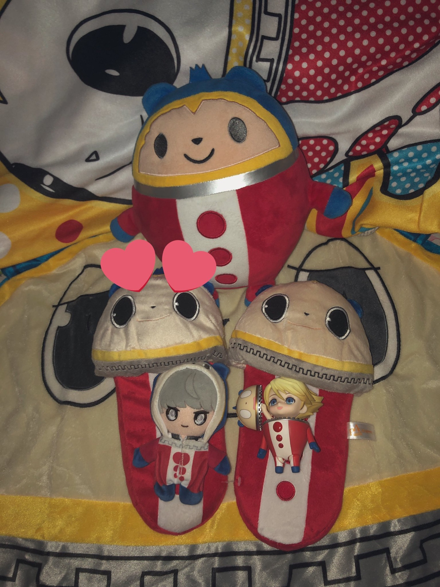 Various merch placed on a blanket of Teddie from Persona 4