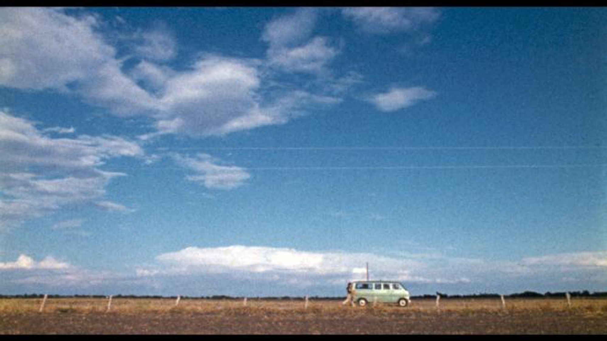 Green 1970s van picking up hitchhiker by the side of a country road