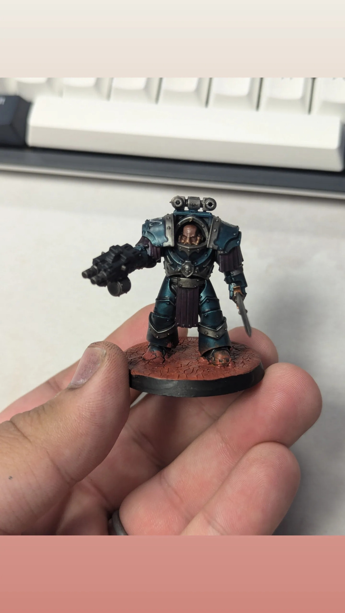 A space marine mini in bulky terminator armour painted a metallic light blue scented with silver and purple fabric on a martian base