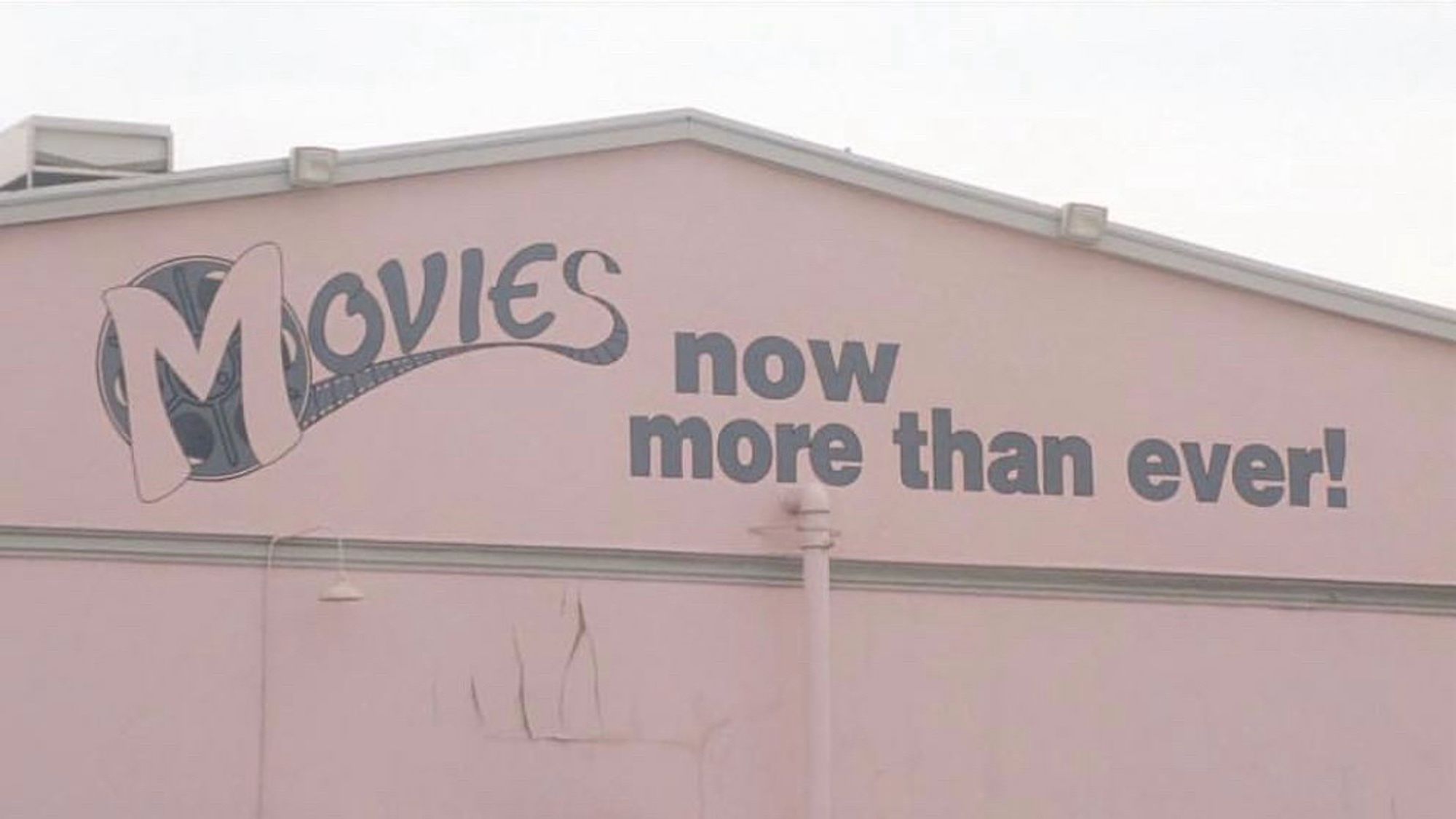 Outside shot of a soundstage in THE PLAYER with “Movies now more than ever” painted on it.