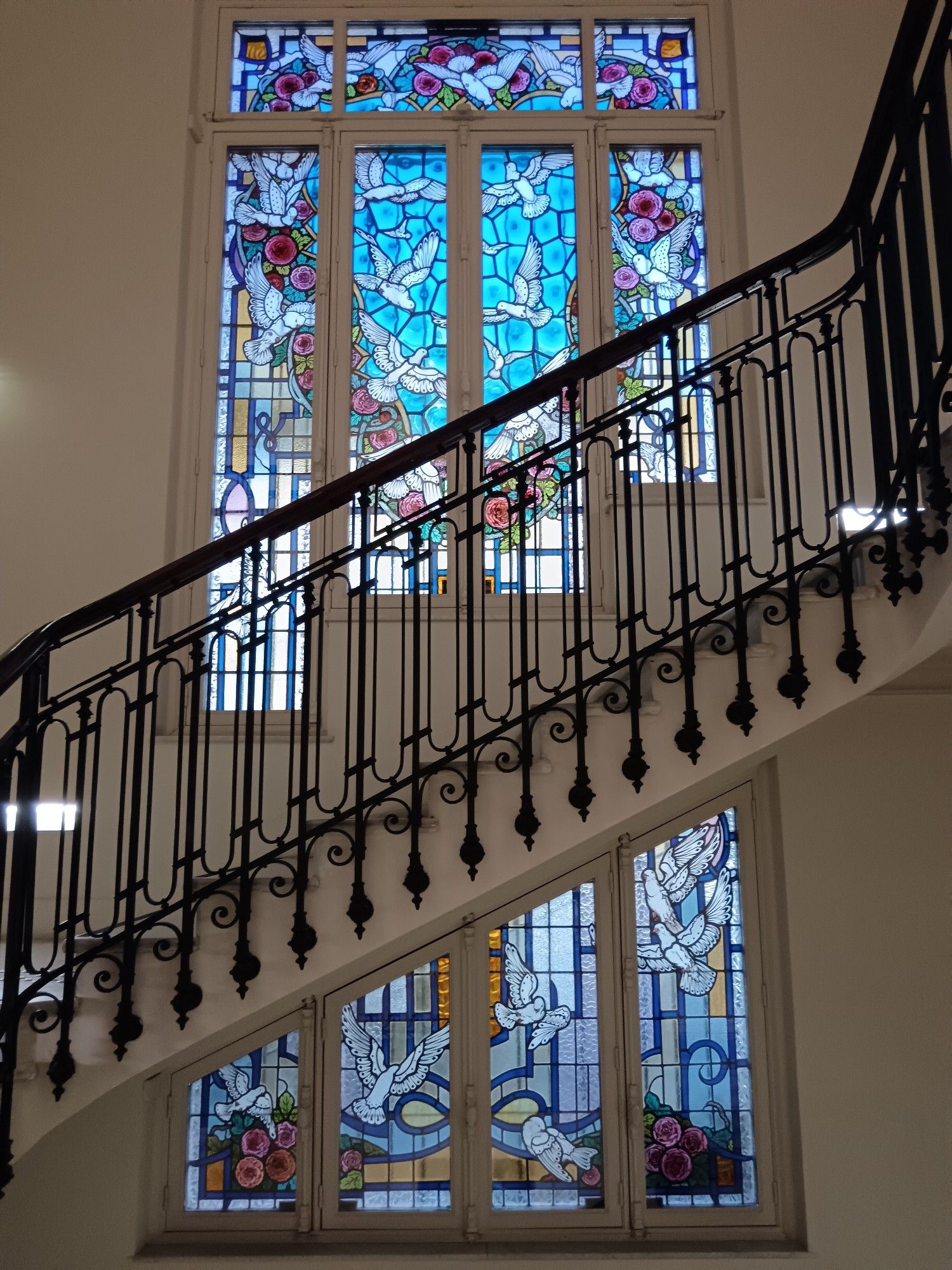 Un grand escalier. Derrière, un vitrail et la lumière.