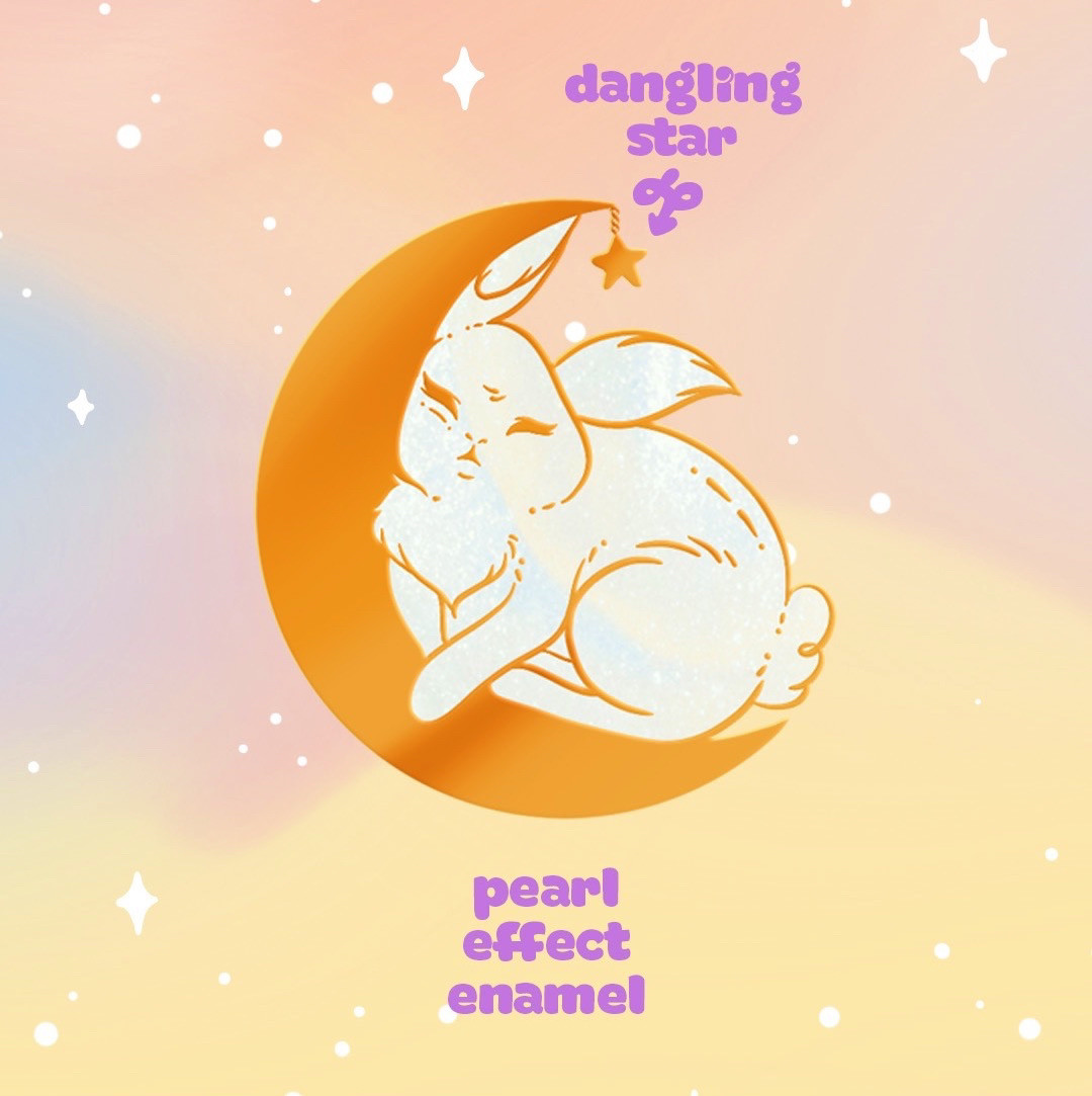 A digital illustration of a golden enamel pin of a bunny sleeping inside a golden crescent moon. The enamel is a pearly variety and a small star dangles from the top of the moon. It’s set on a pastel cloudy background.