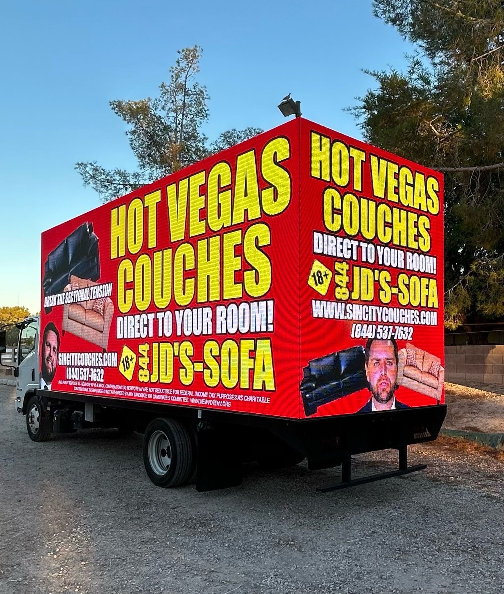 billboard truck that says "hot vegas couches direct to your room!" "break the sectional tension" with two couches and a photo of JD vance. there is also a phone number 844-JD's-SOFA or 844-537-7632 and an 18+ logo and sincitycouches.com