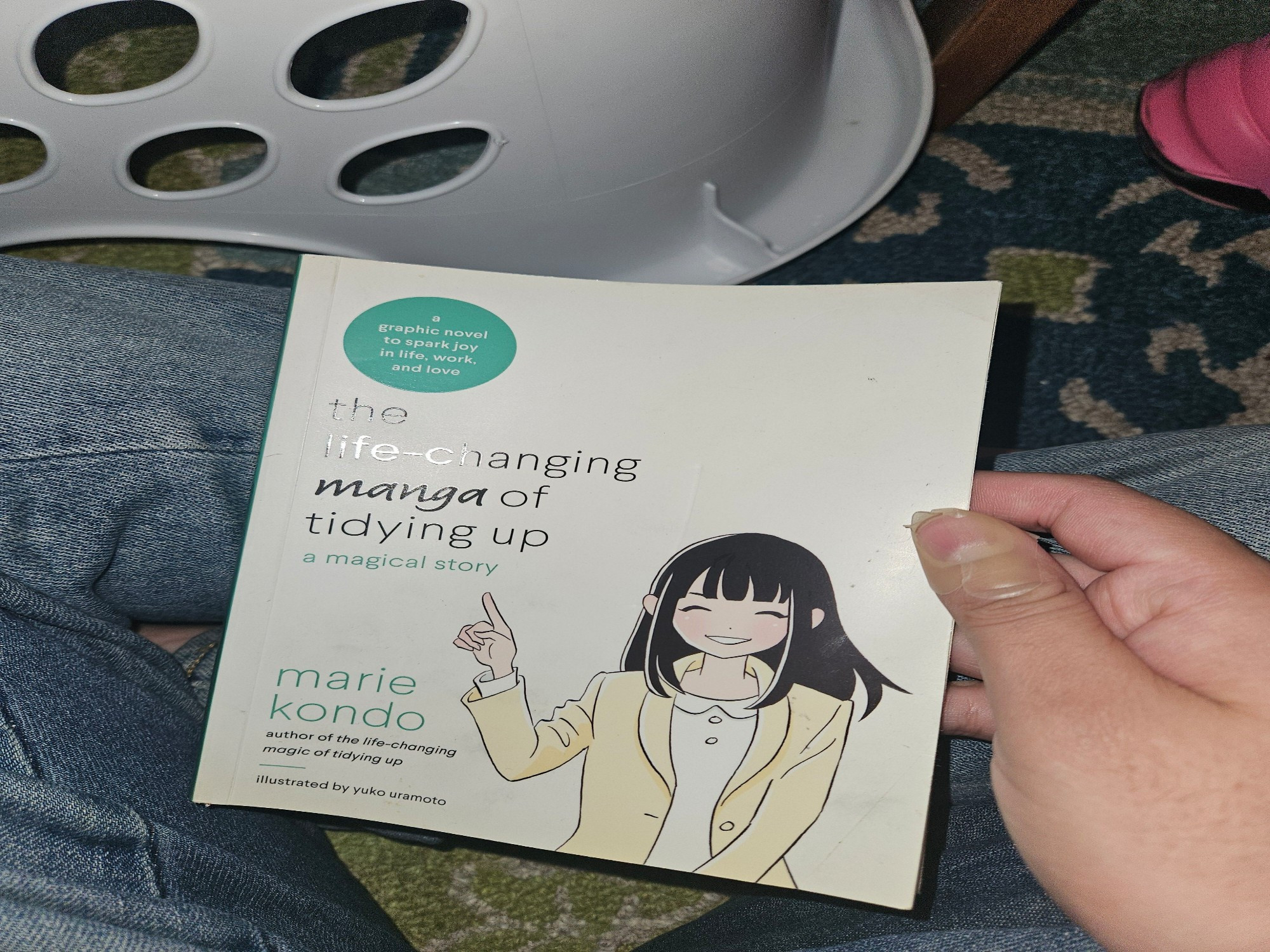 Amidst the rubble of laundry, david holds "The life-changing manga of tidying up: a magical story" by Marie Kondo and illustrated by Yuko Uramoto