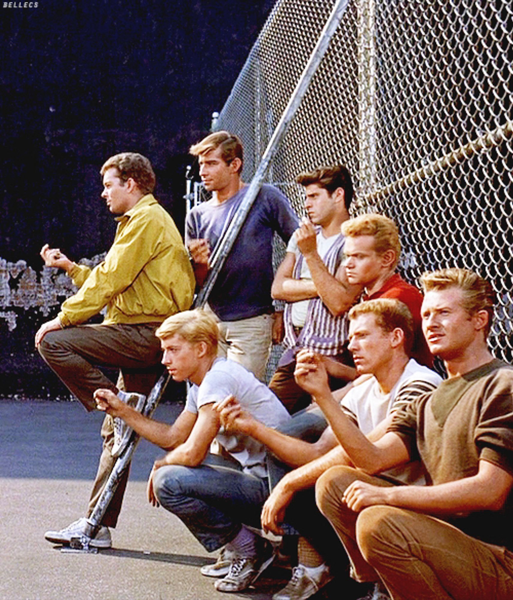 A scene from “West Side Story” of the Jets in a courtyard leaning against a chain link fence and snapping their fingers together. They’re going to face the Sharks real soon.