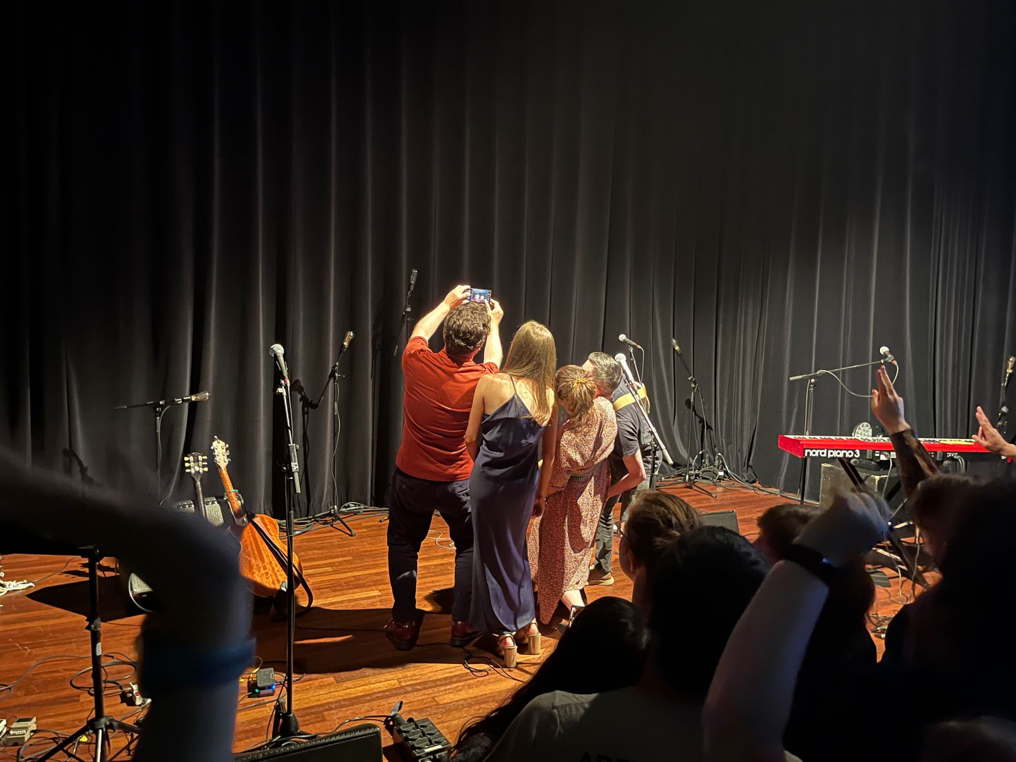 The four band members of IMLÉ taking a selfie with the audience leaning backwards with a camera