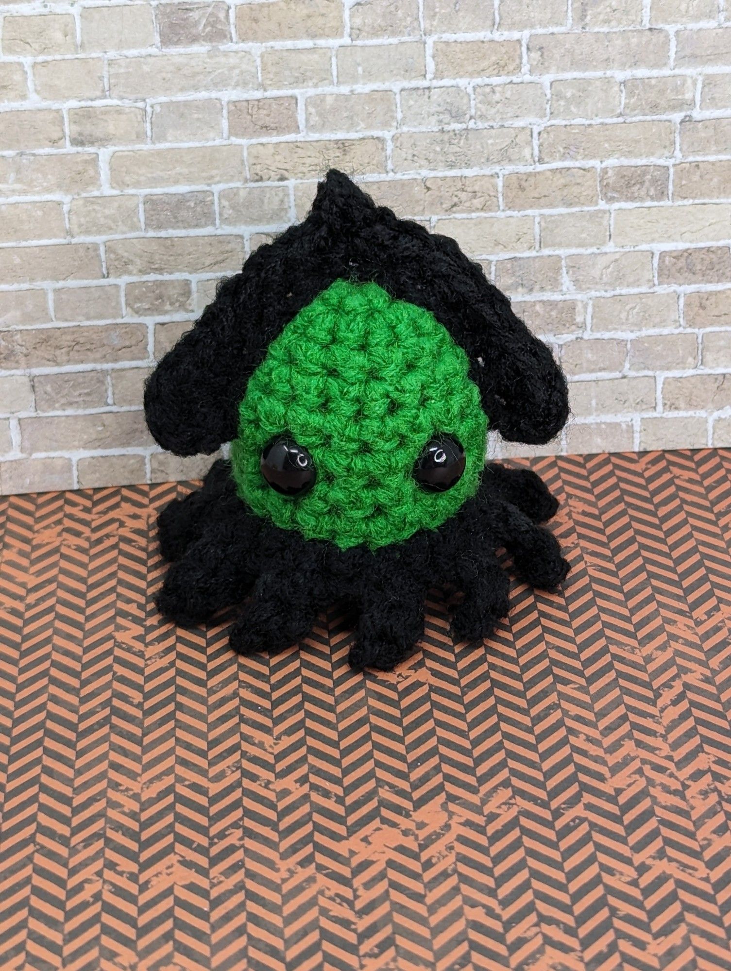 A green and black crocheted squid