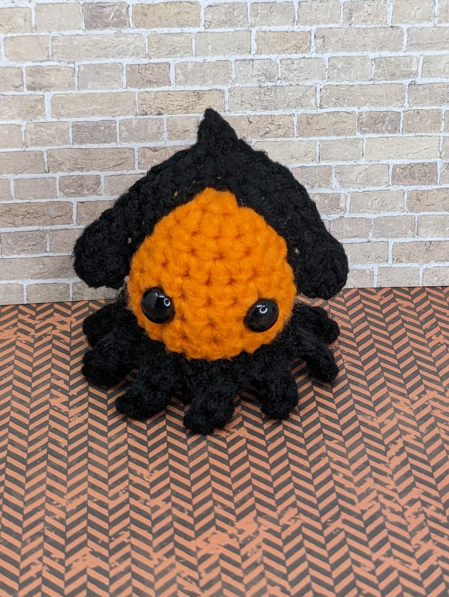 An orange and black crocheted squid