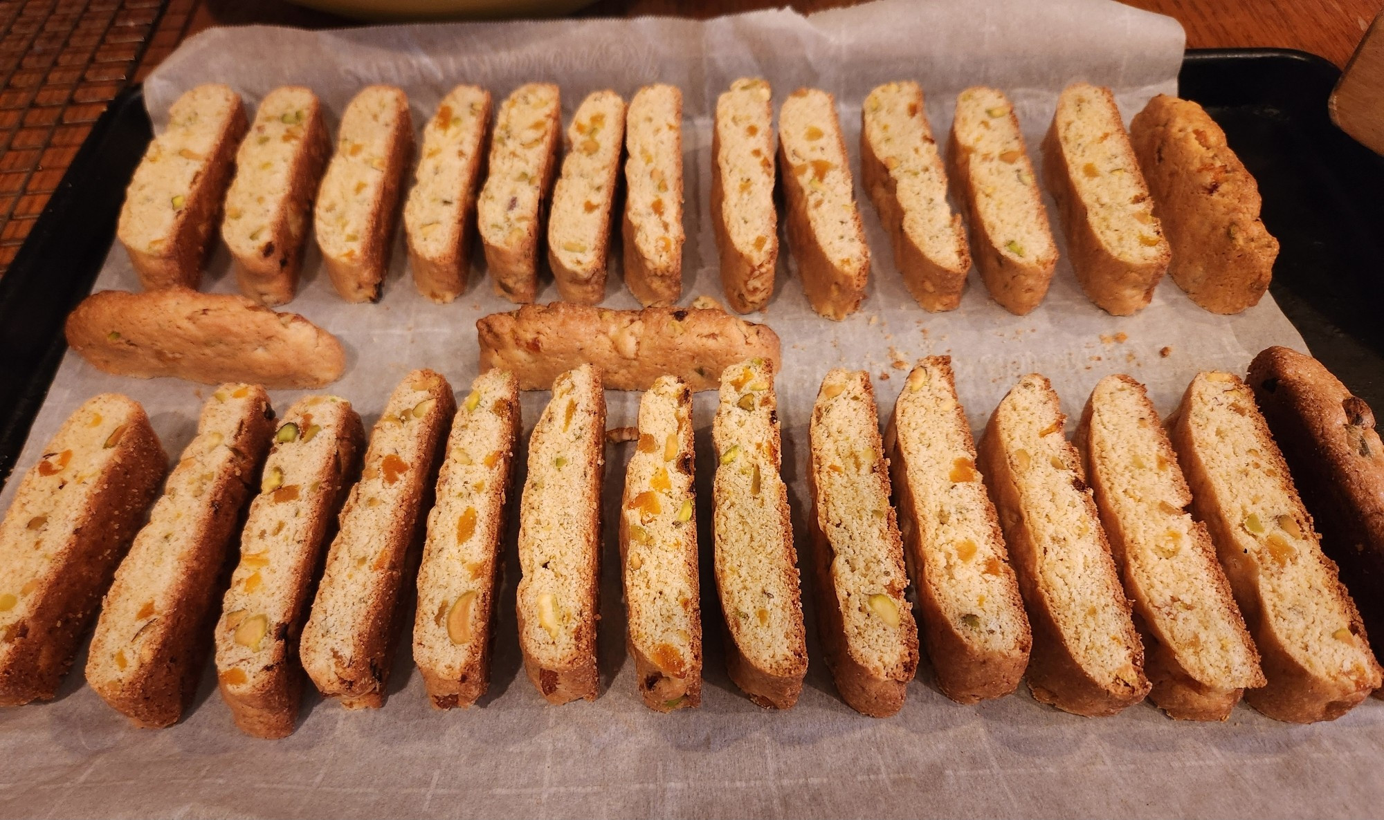 Two rows of biscotti pieces on a parchment lined baking sheet