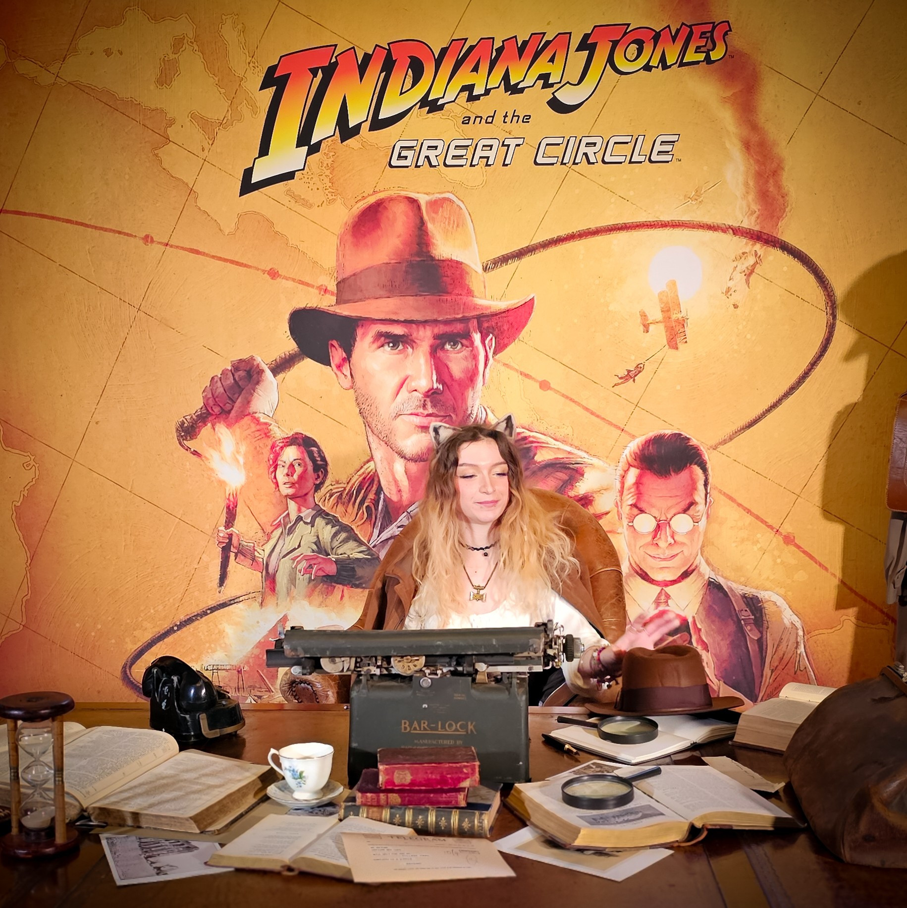 A picture of me reaching for Indiana Jones hat sitting at a desk. The game art is behind me!