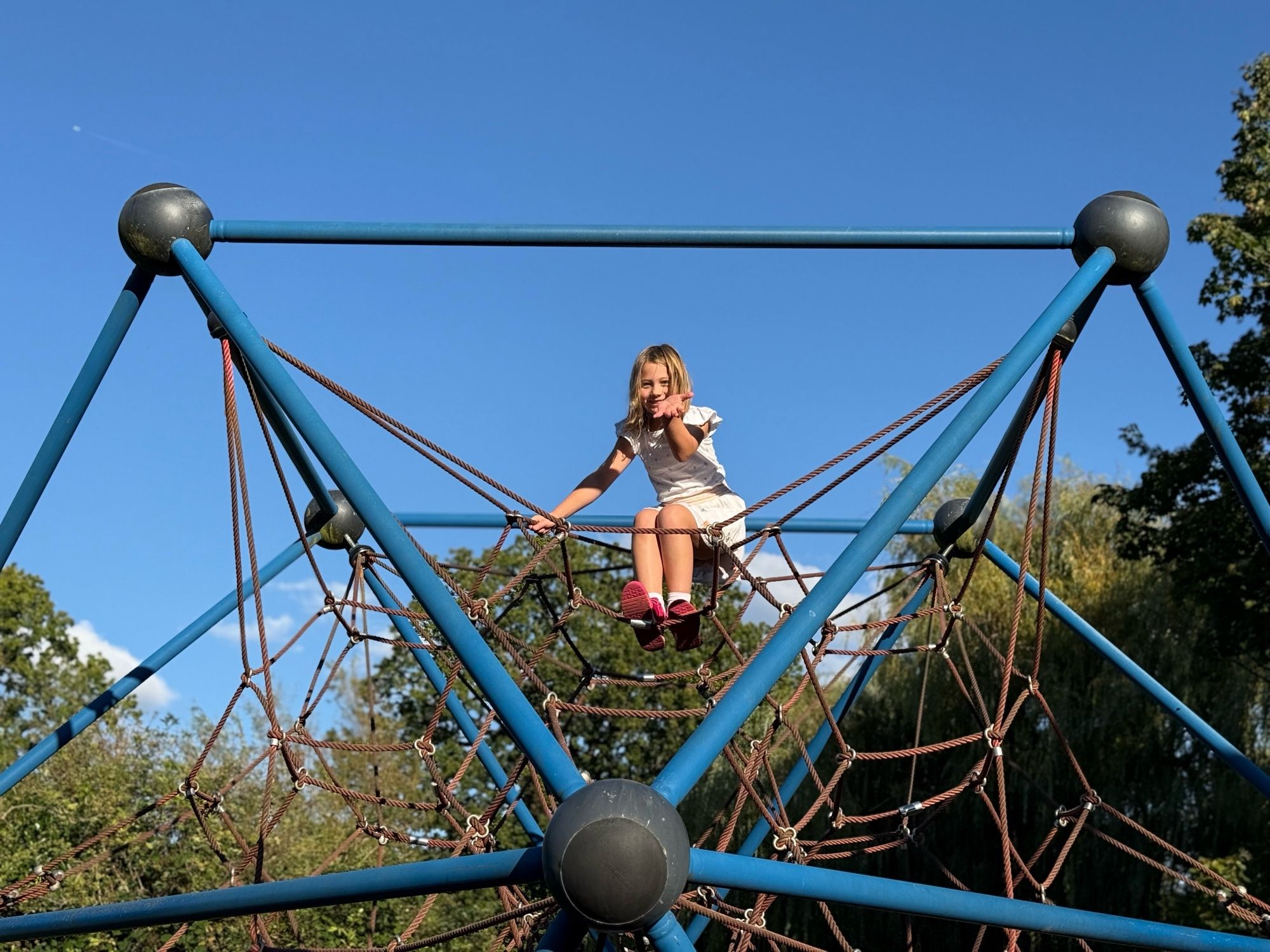 Happy child at top of climbing frame.