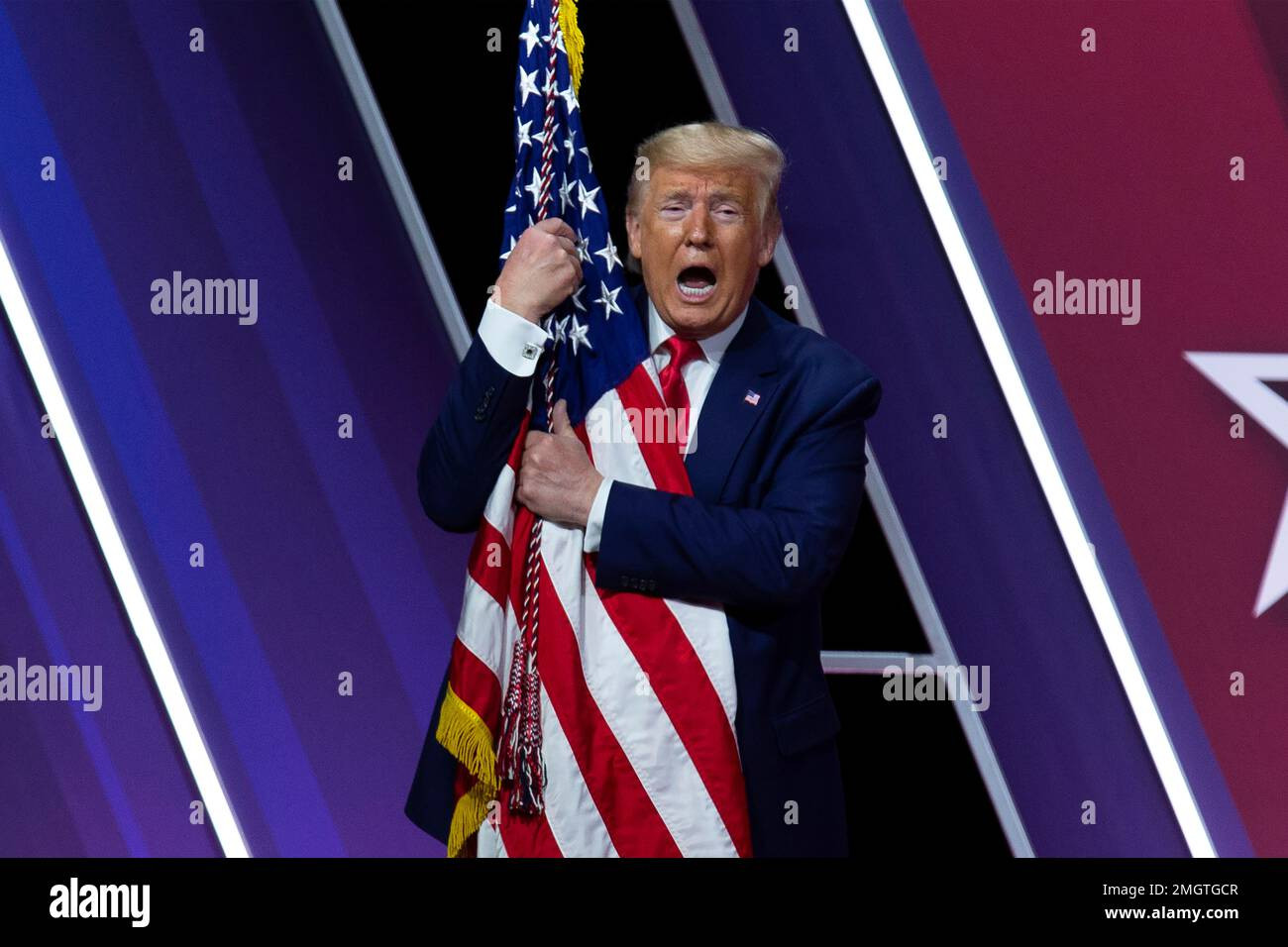 Trump having an accident while hiding behind a flag to cover his pants.