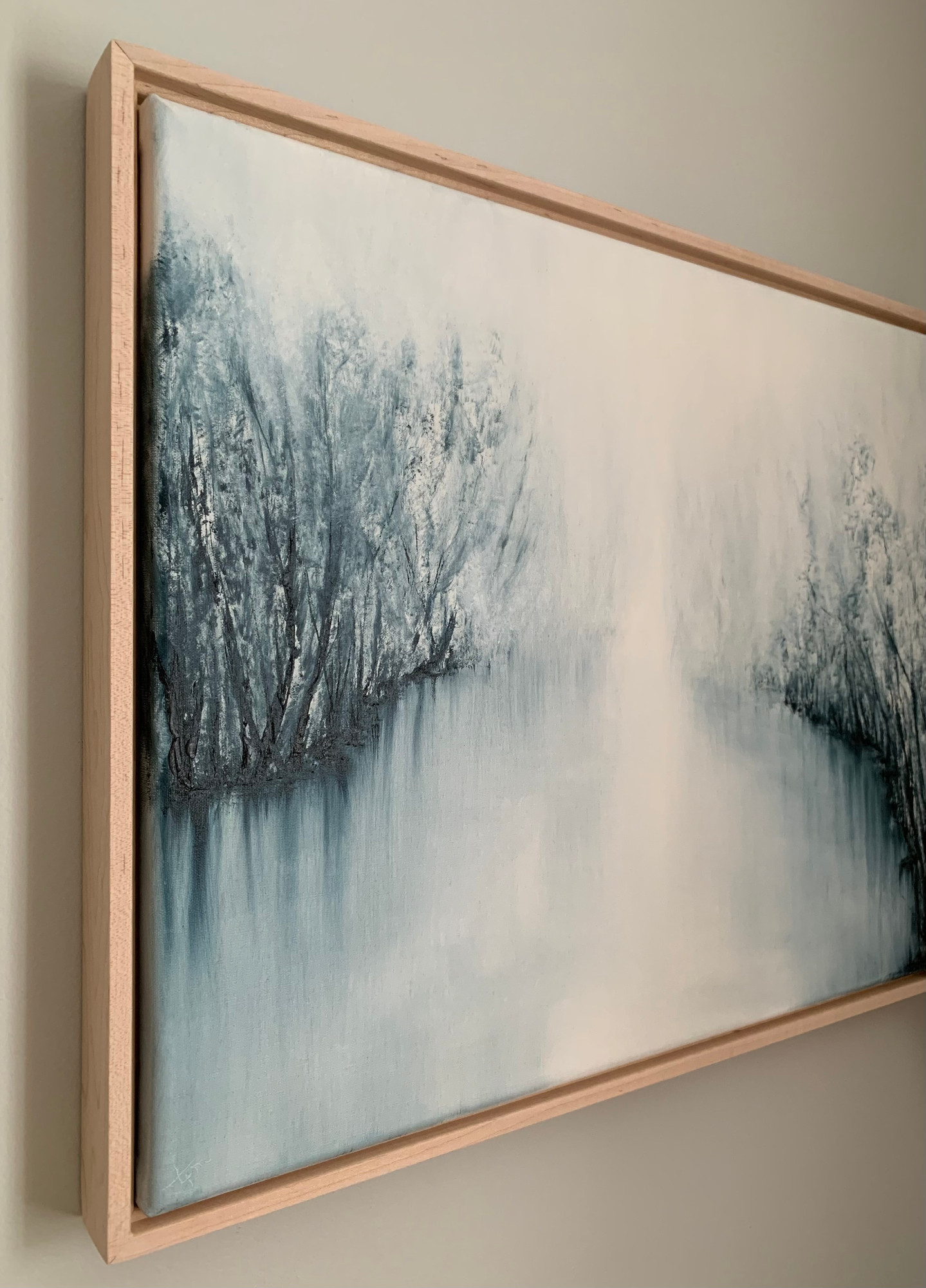 Original oil painting by Tisha Mark, "The Space Between" 16"x20" oil on linen (2023), shown in a maple floater frame at an angle from left. Abstract foggy landscape painting, painted in a limited palette of blues and whites.