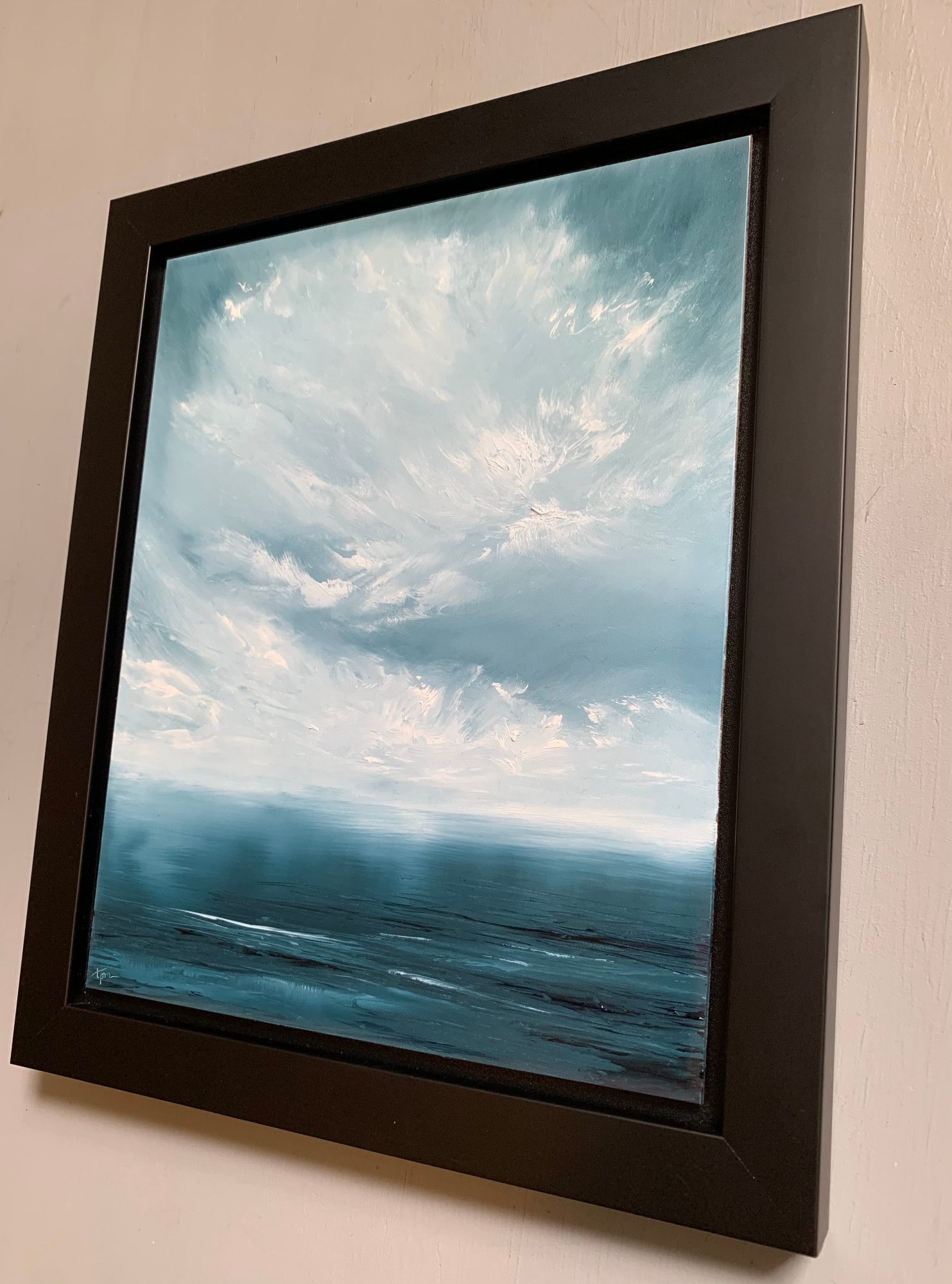 Original seascape oil painting by Tisha Mark, "A Day for Dreams" oil on Ampersand Gessobord, 10"x8" (2024), shown in a black frame at an angle from right. This seascape with a color palette of vibrant blues and whites was inspired by a walk along a calm sea underneath a dreamy, atmospheric sky.