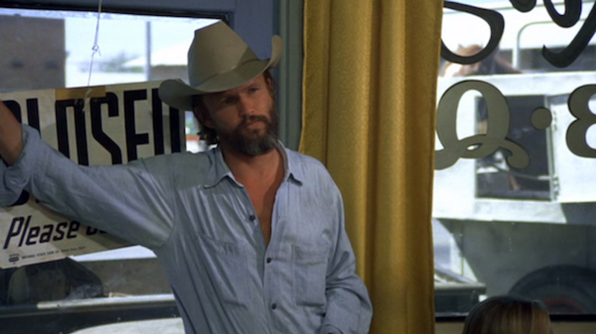 Kris Kristofferson in Alice Doesn't Live Here Anymore, leaning against the doorway of a diner with a beard and a cowboy hat & looking extremely fine.