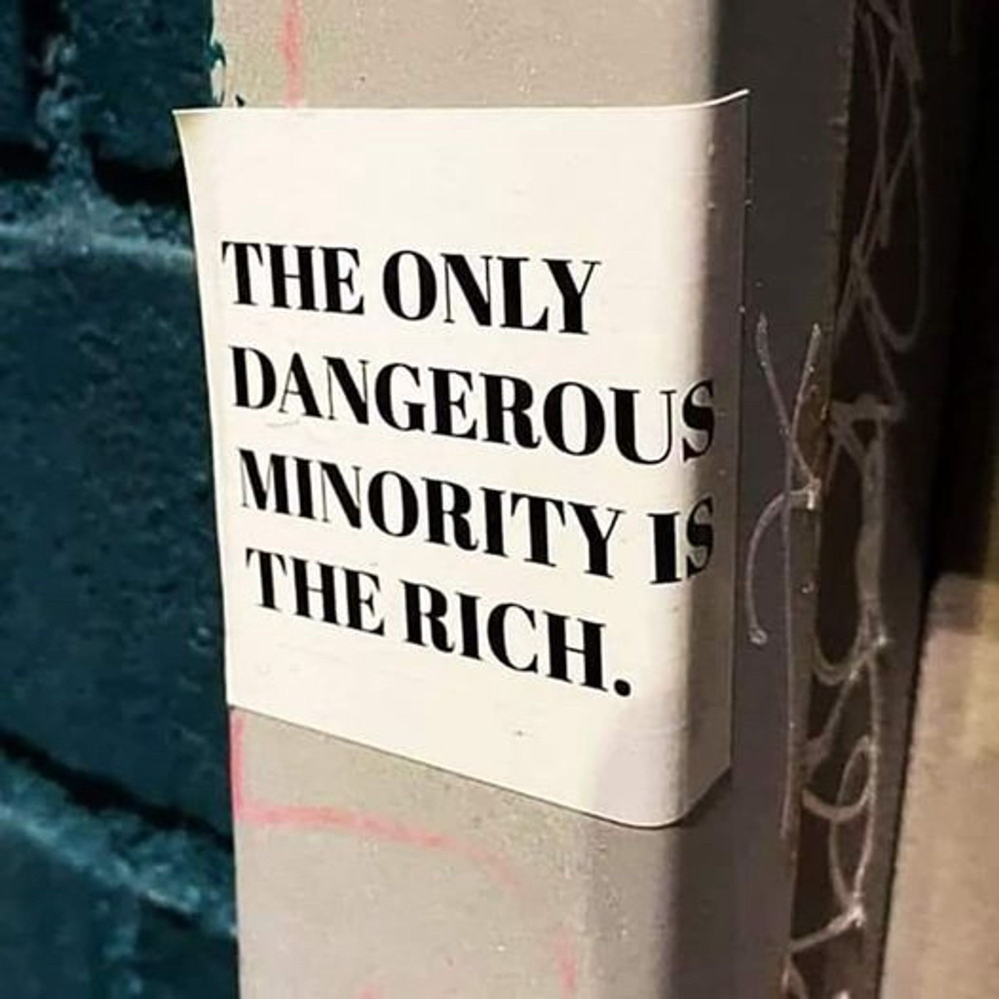 Post with sticker that reads: The only dangerous minority is the rich.