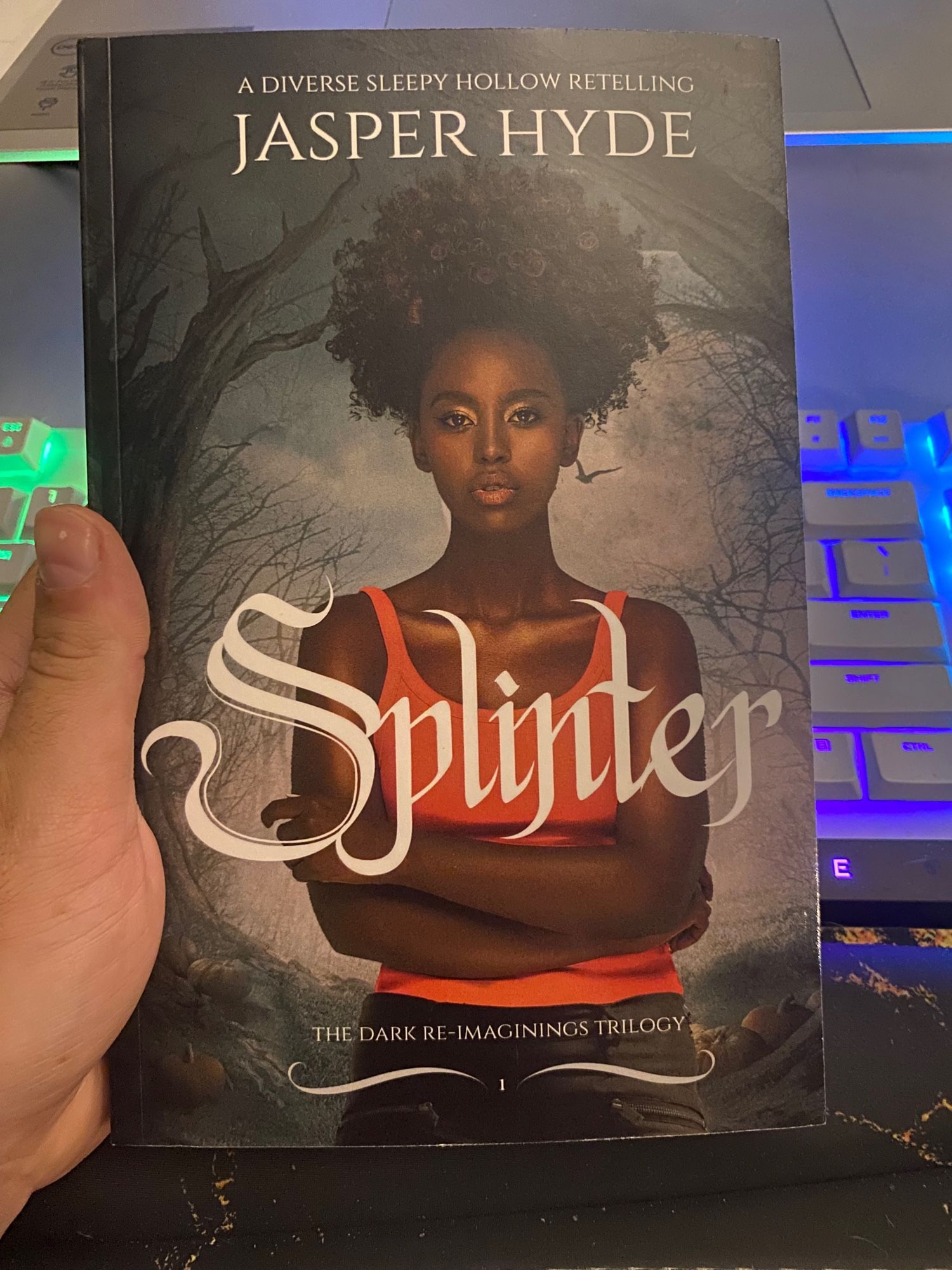 Cover of the book Splinter by Jasper Hyde. Cover features a black person with her arms crossed and wearing an orange tank top (using pronouns that match the blurb on the back as I haven't read the book yet and do not know this character's identity yet)