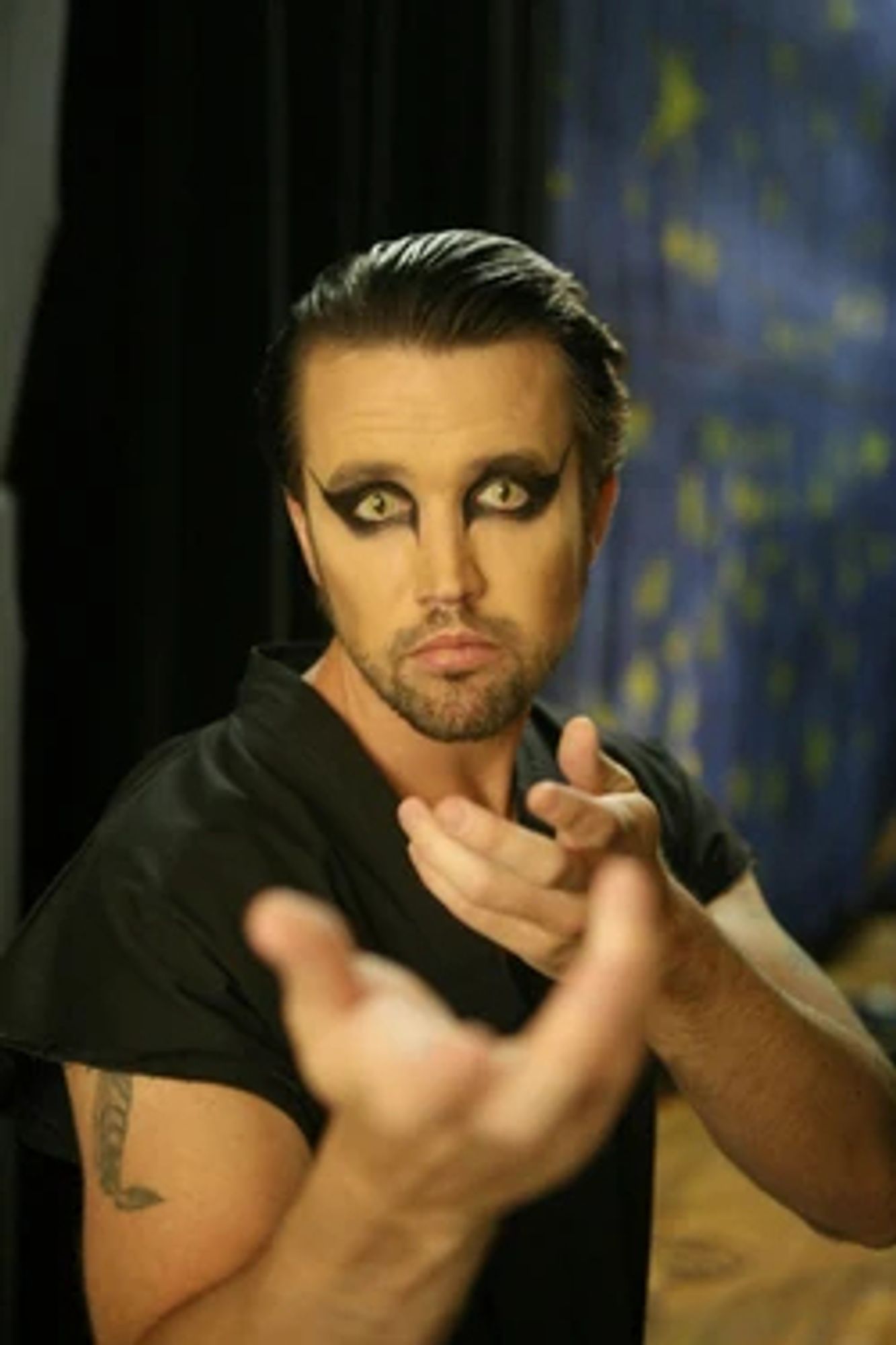 mac from always sunny as the nightman with his cat eyes looking insane. he is beseeching something