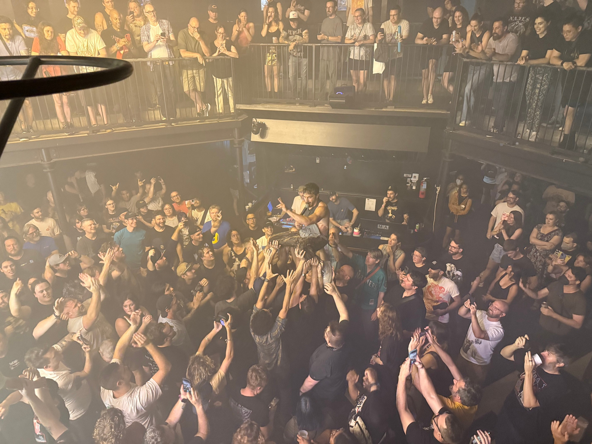 A crowd at a punk show holds up the lead singer of the band