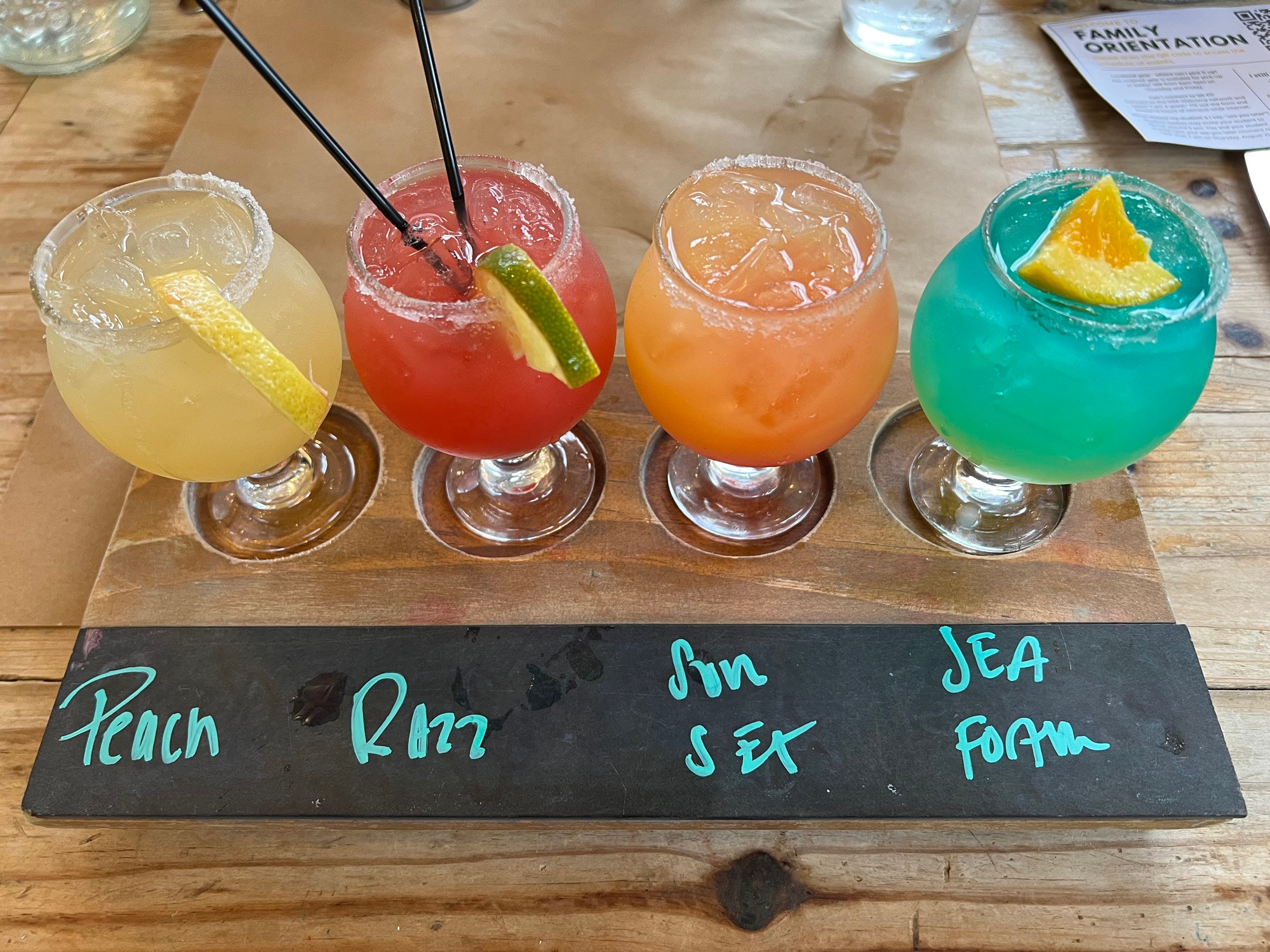 A flight of four 5-ounce margaritas labeled peach, razz, sunset, and sea foam